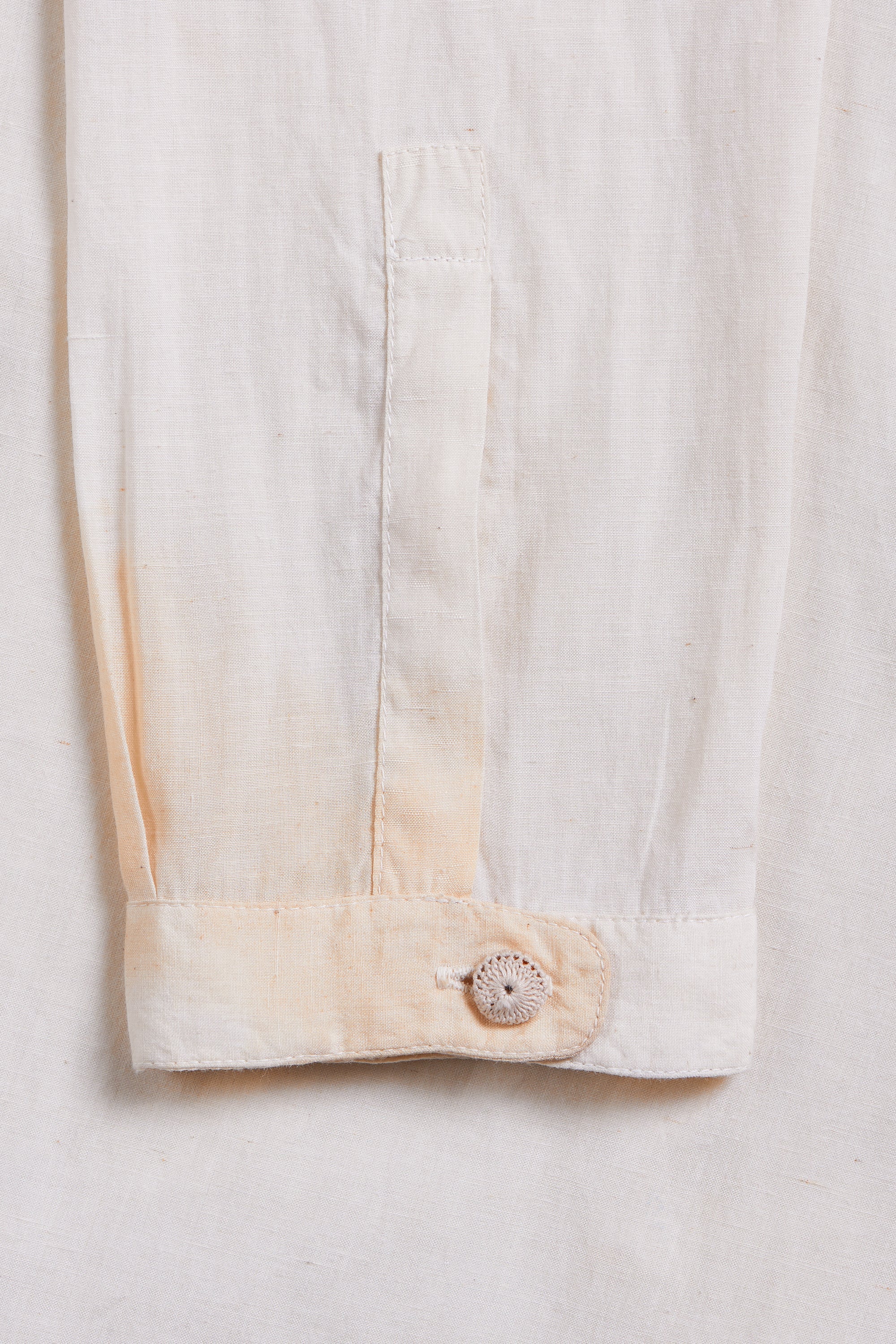 Close-up of a button on a light-colored fabric garment with a plain background
