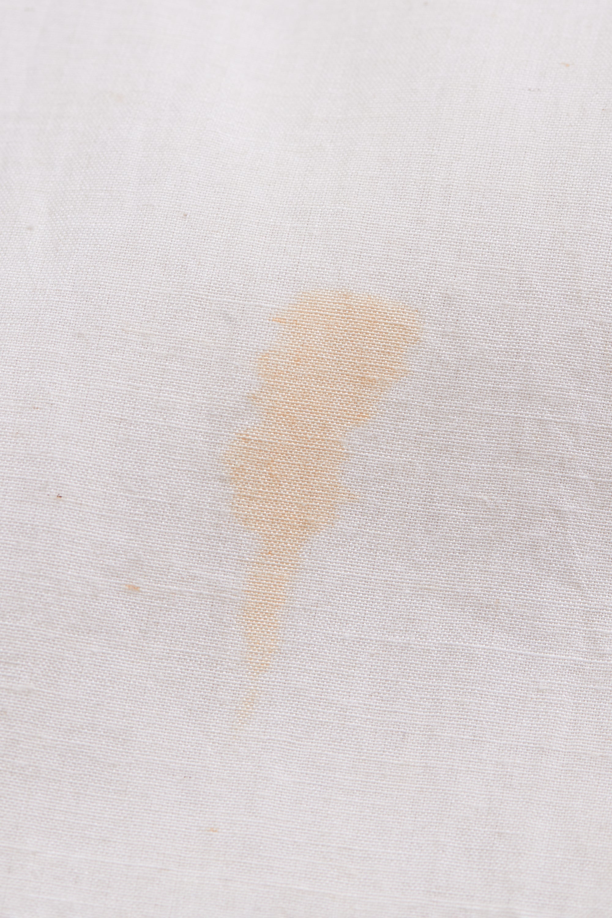 Small beige stain on a white fabric surface