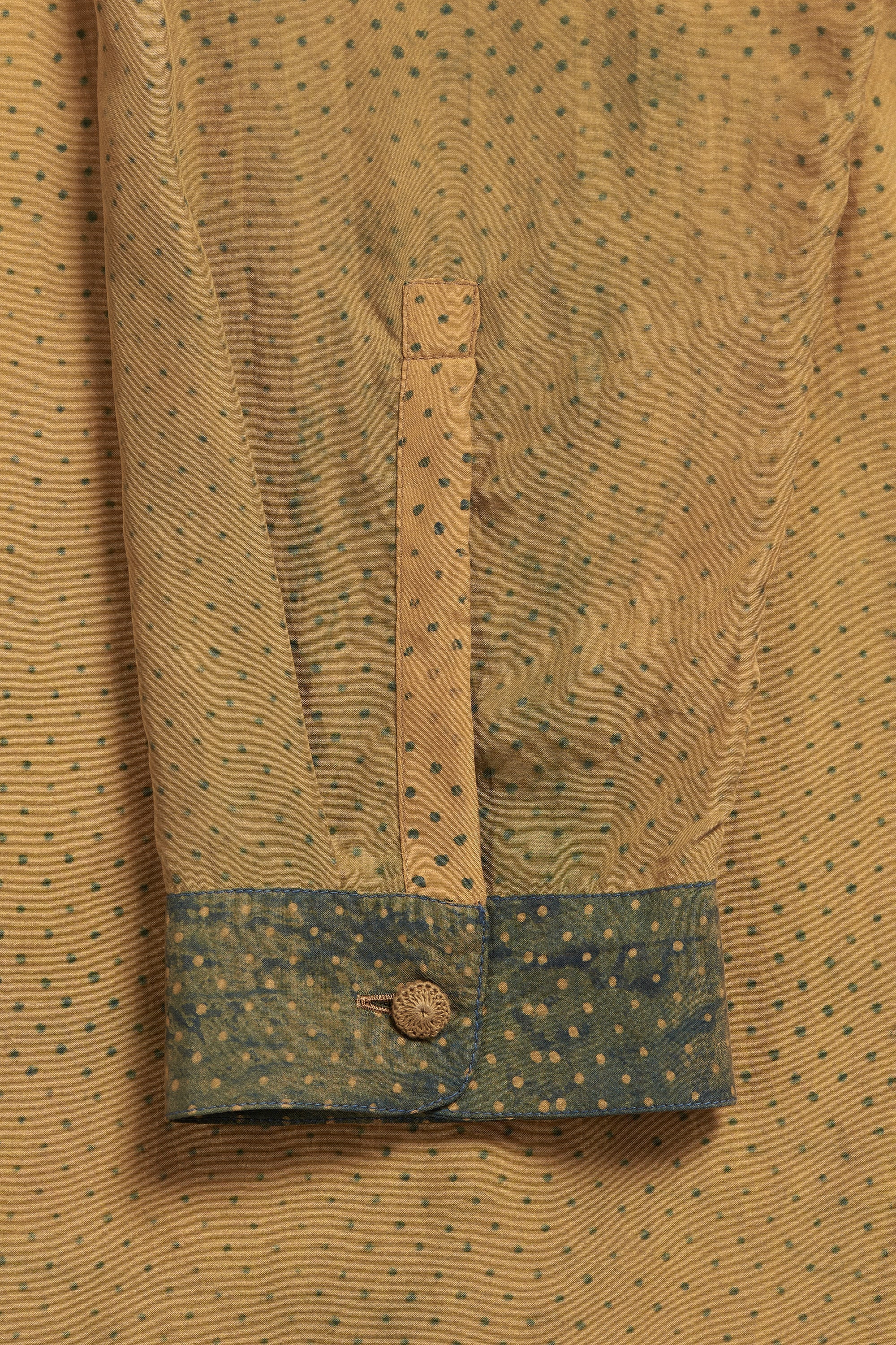 Close-up of a patterned shirt with a button on a beige background