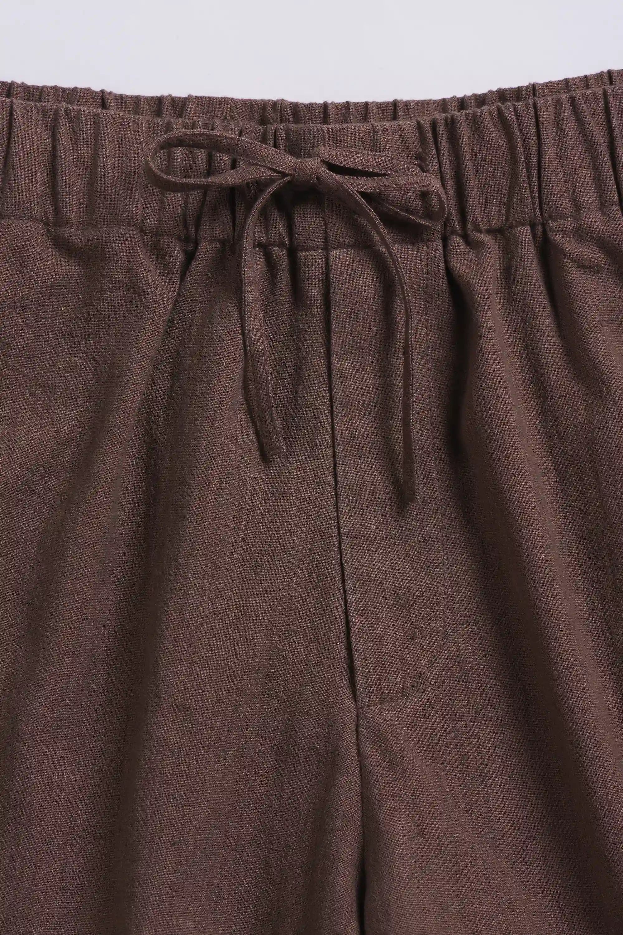 Brown pants with a drawstring waist on a light grey background