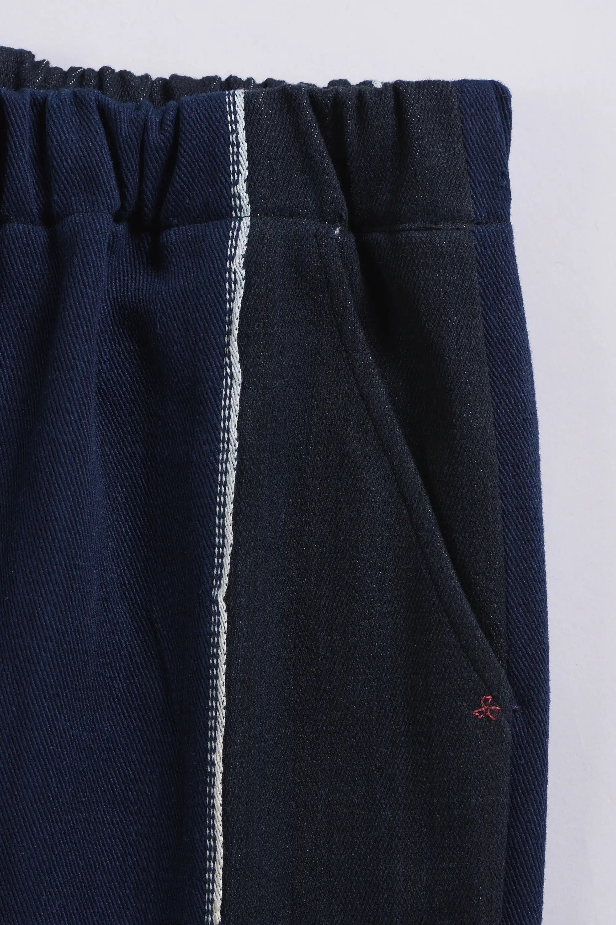 Indigo pants with a white stripe on a light grey background