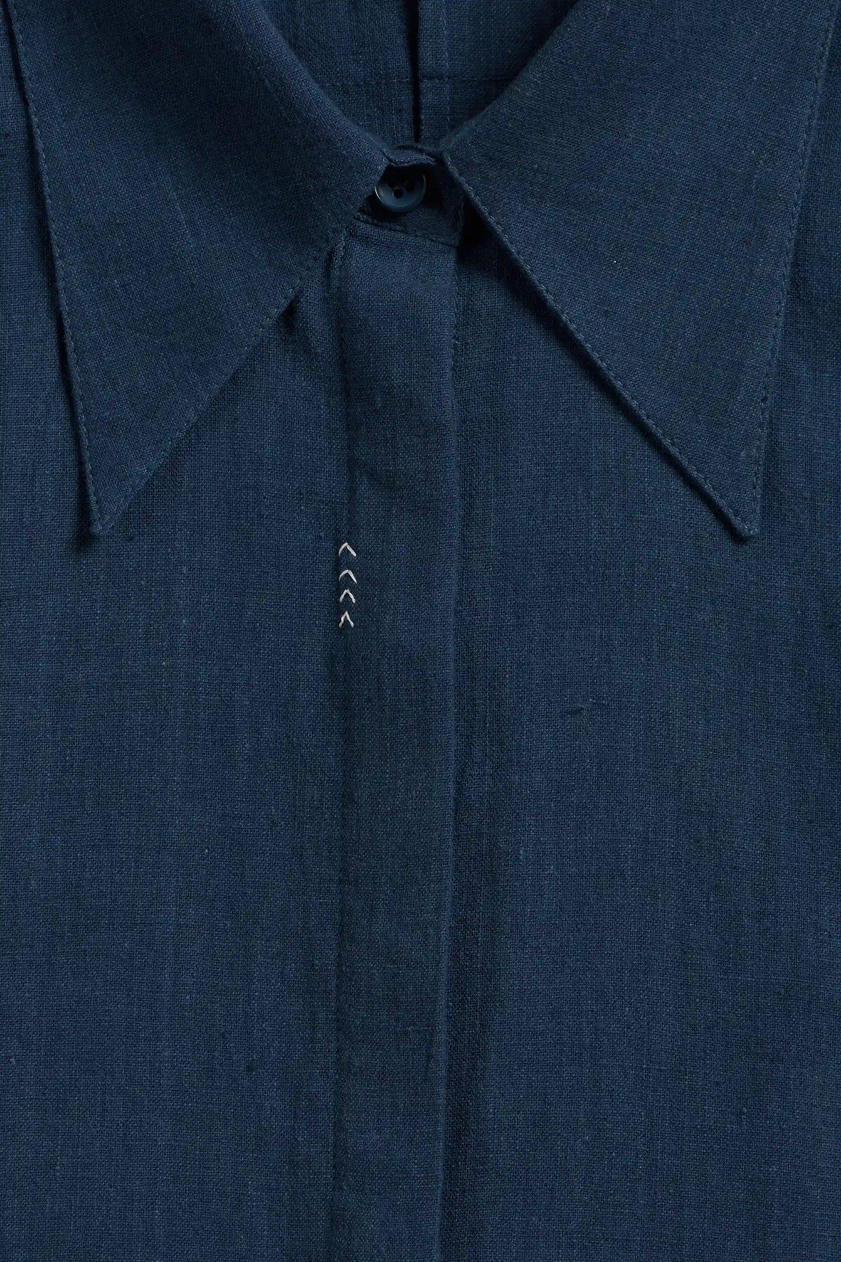 Close-up of a space blue button-down shirt showing the collar, button, and fine fabric texture.