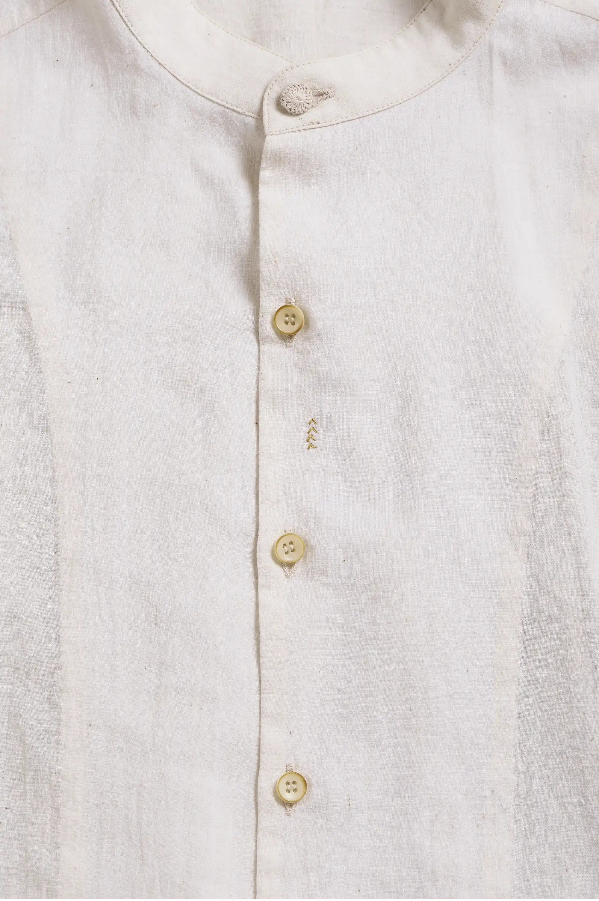 Close-up of a ecru shirt with buttons on a light grey background