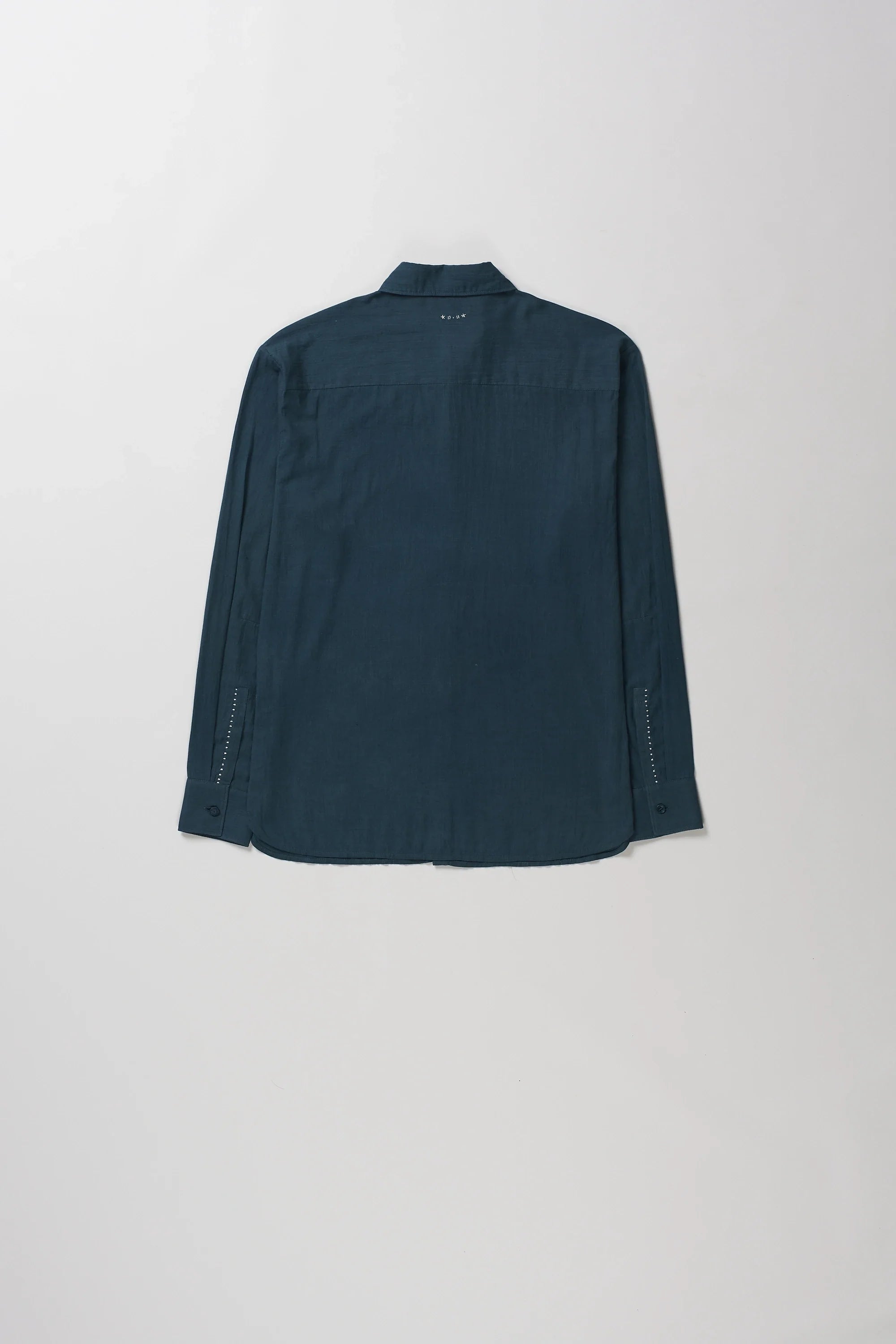 Back shot of long-sleeve button-up shirt with a pointed collar, laid flat against a light gray background.