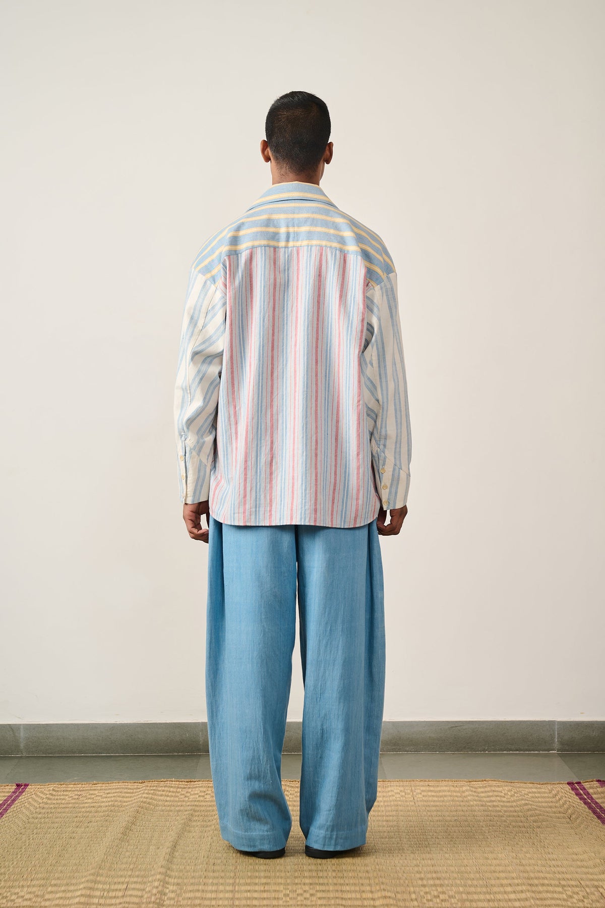A back shot of a man wearing multi colour shirt