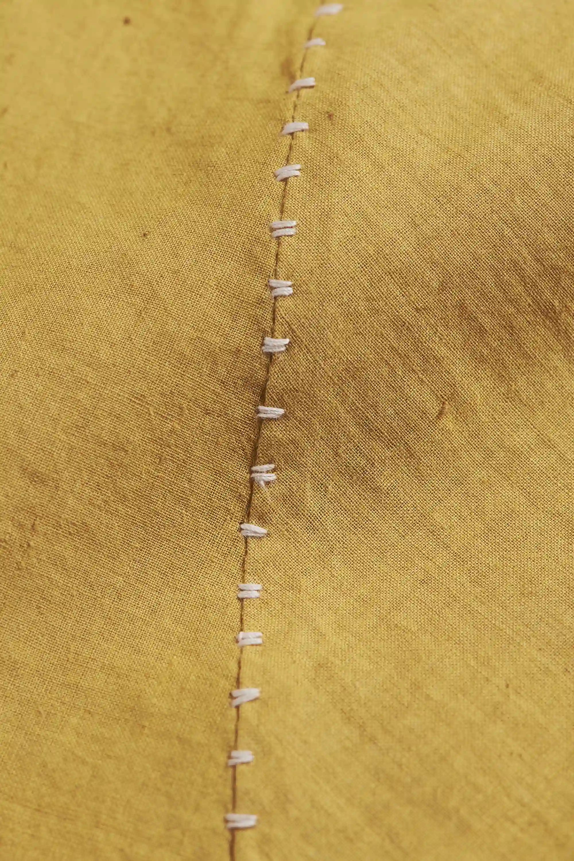 Close-up of a ochre yellow fabric with hand detailing