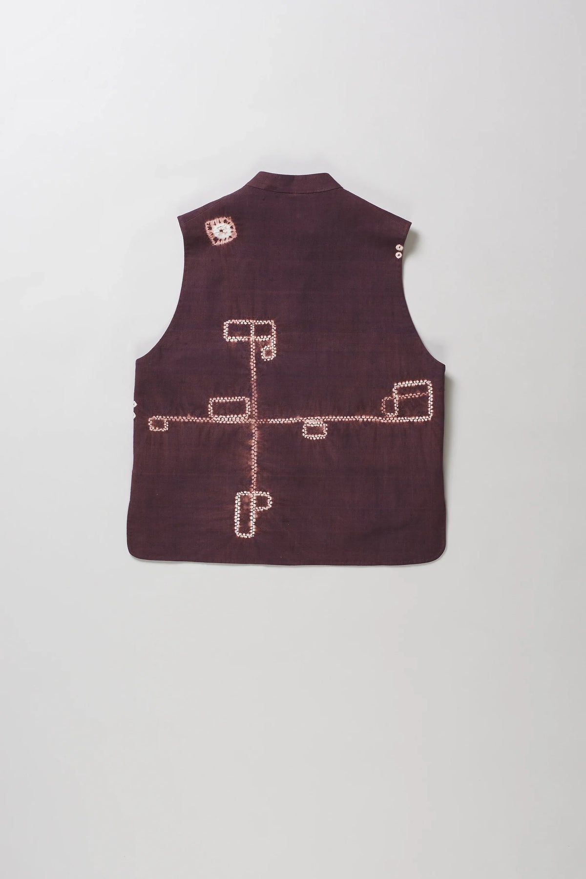 A sleeveless vest with shibori patterns in light colour and white on the back, displayed flat against a light grey background.