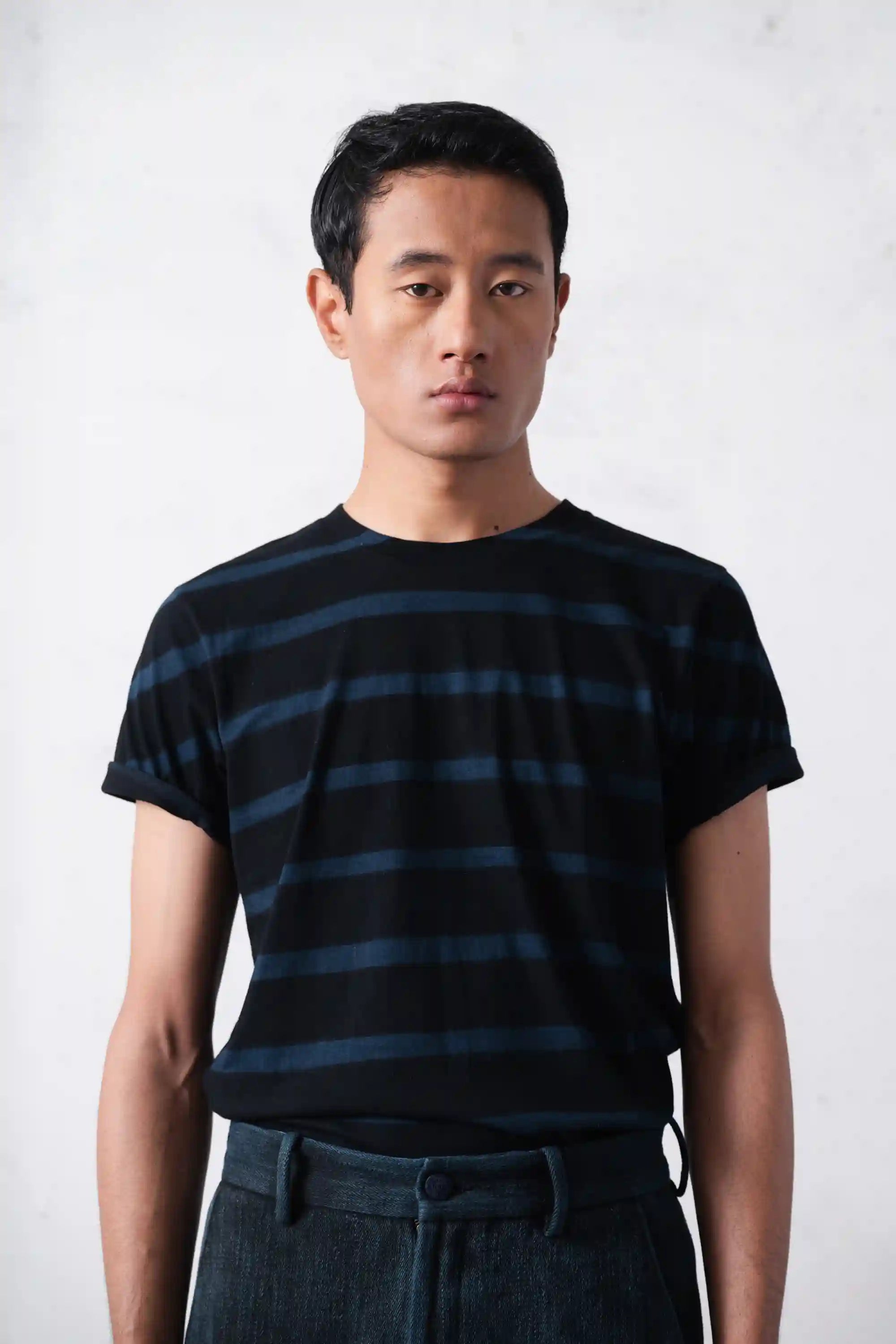 Man wearing a black and blue striped t-shirt against a white background