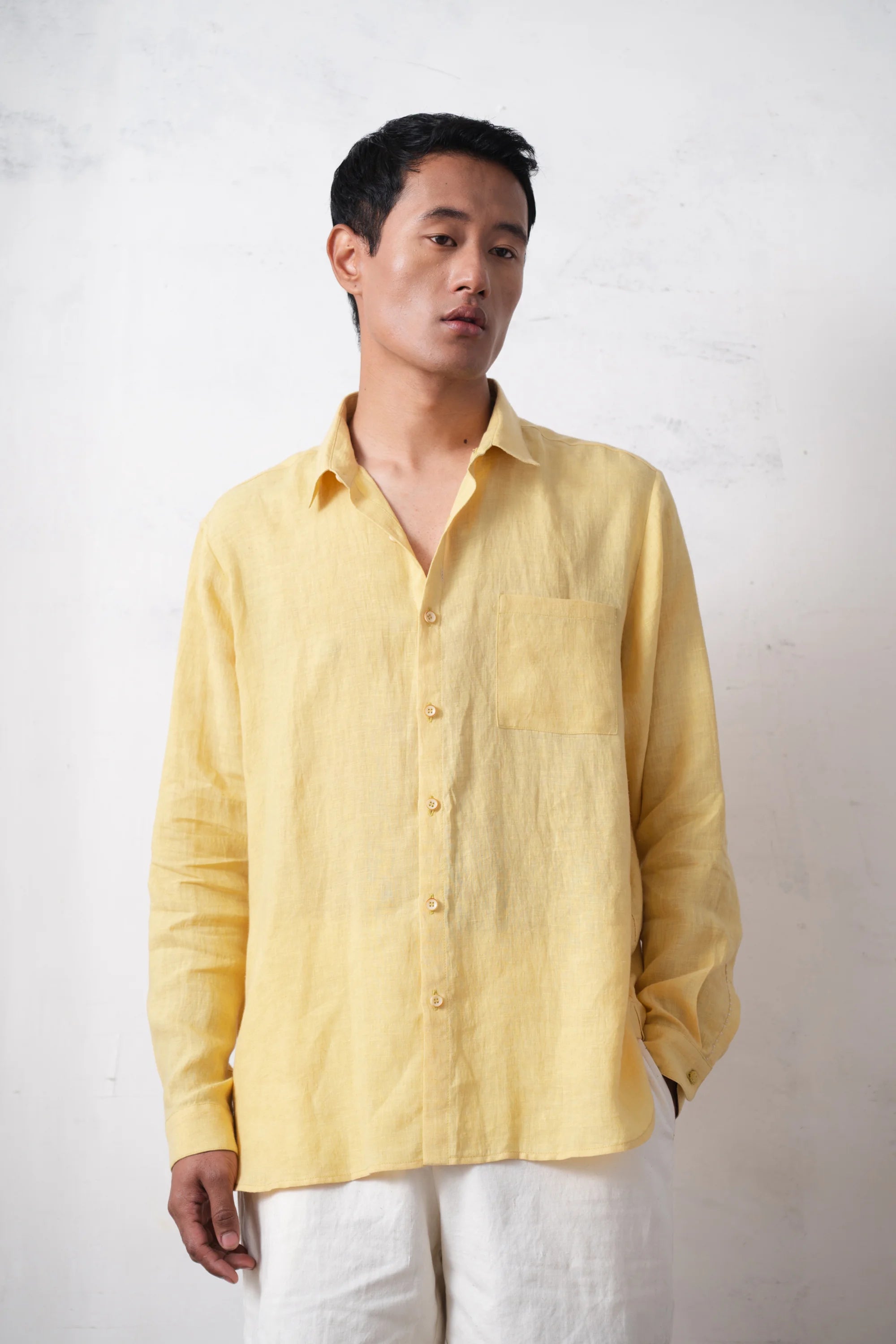 Man wearing a light yellow shirt against a light grey background