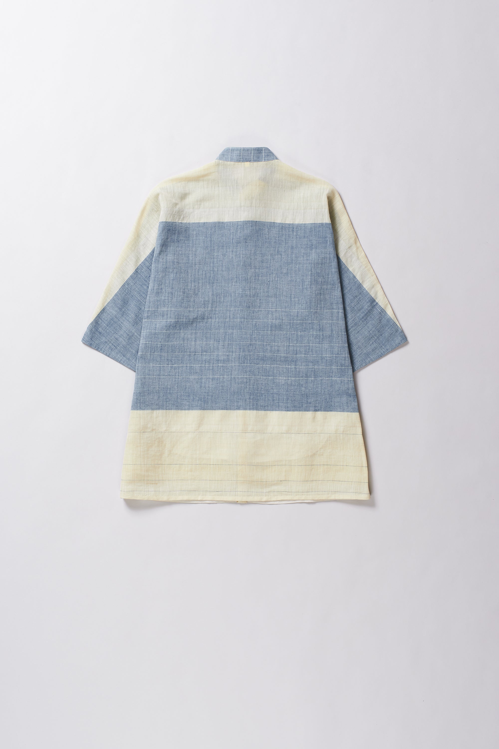 Color-blocked shirt with blue and beige sections on a light grey background