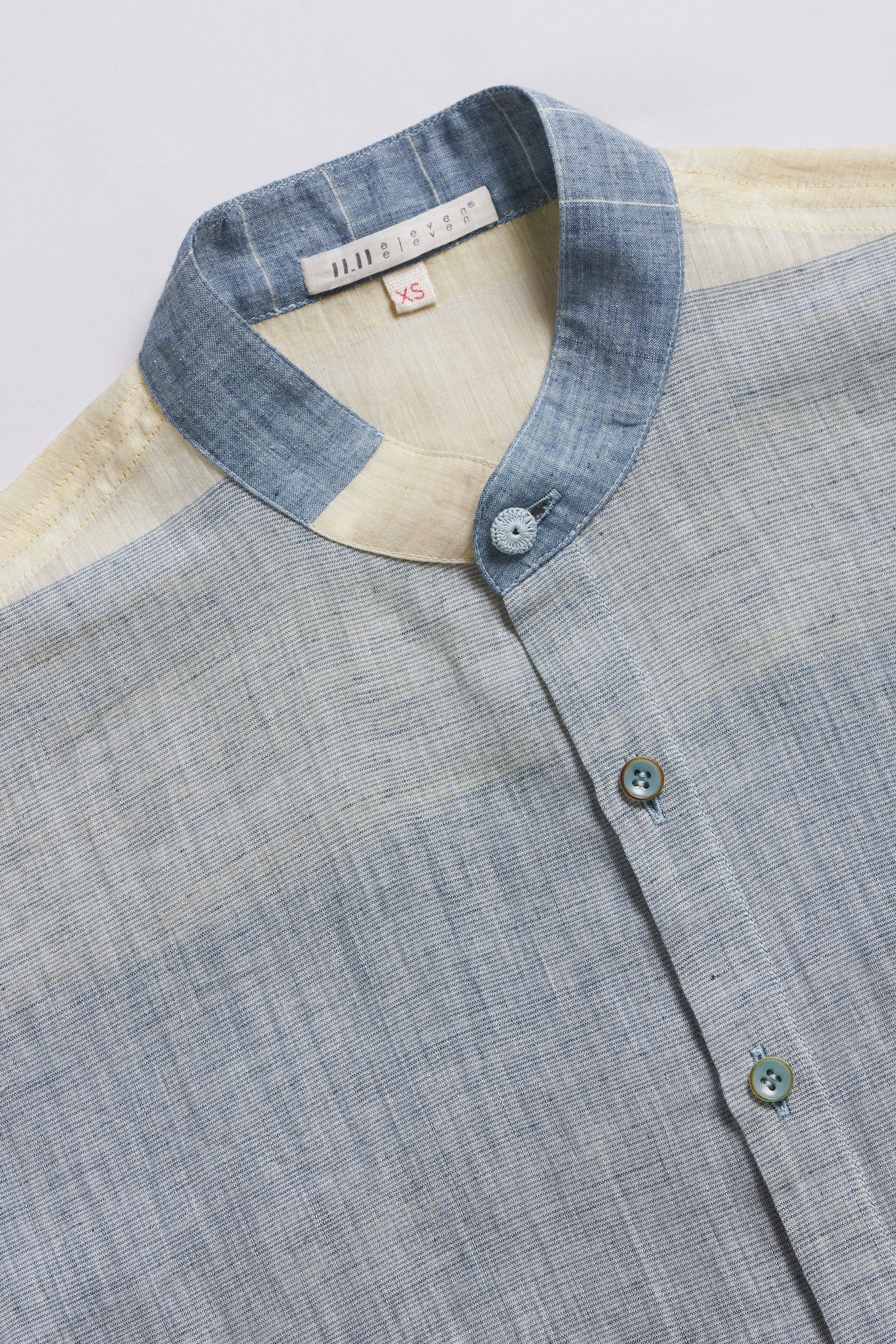 Gray shirt with a blue collar and buttons on a light grey background