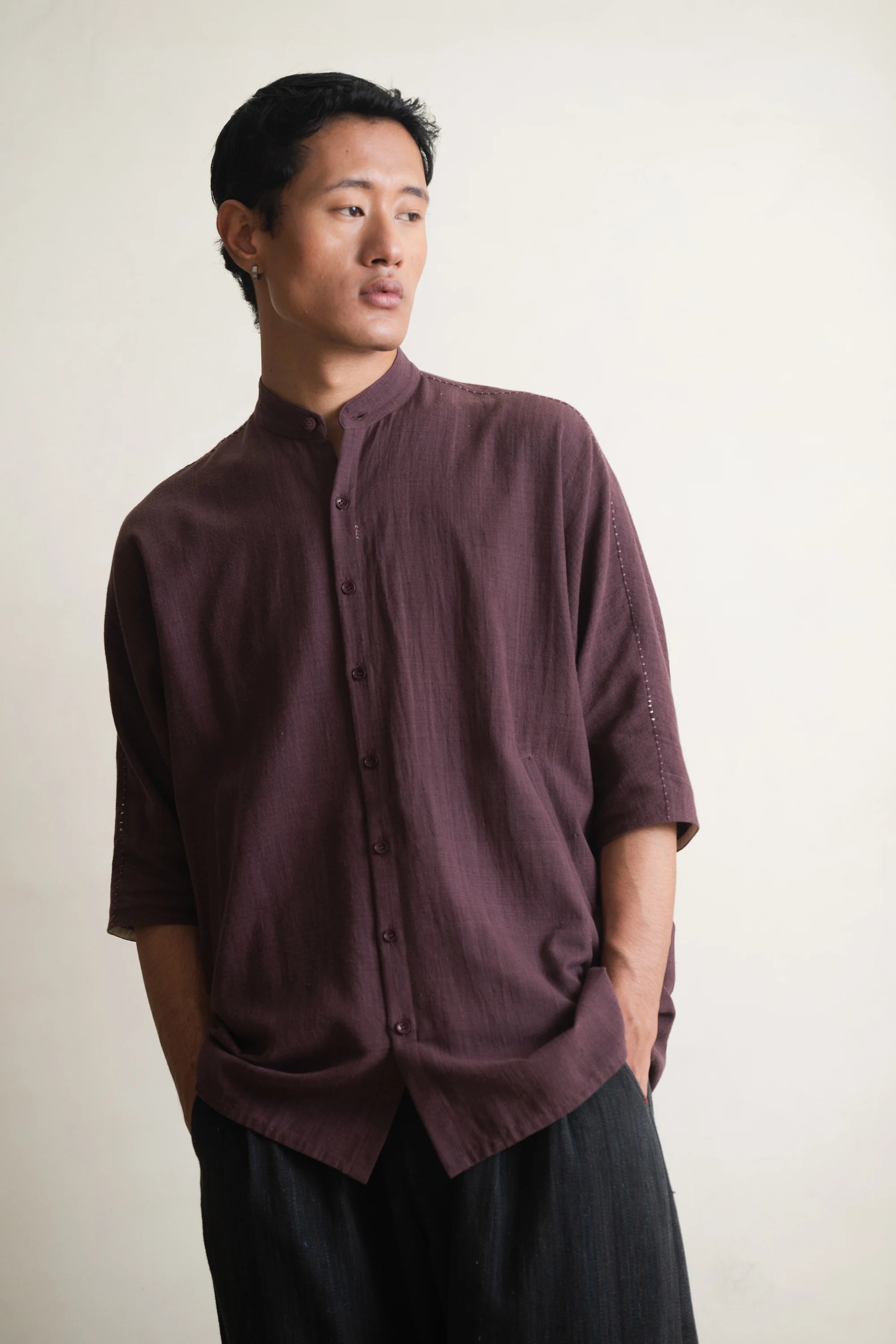 Man wearing a purple red shirt against a light grey background