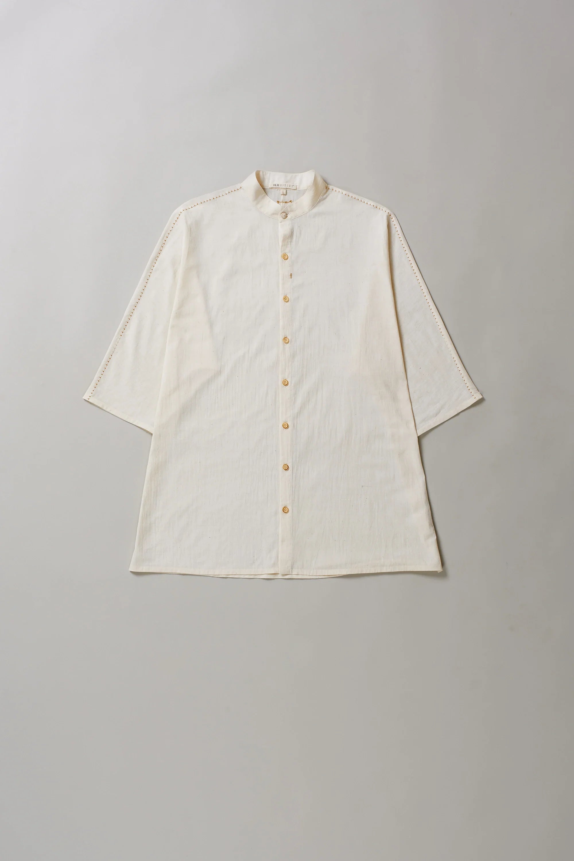 Ecru cotton shirt with buttons on a grey background