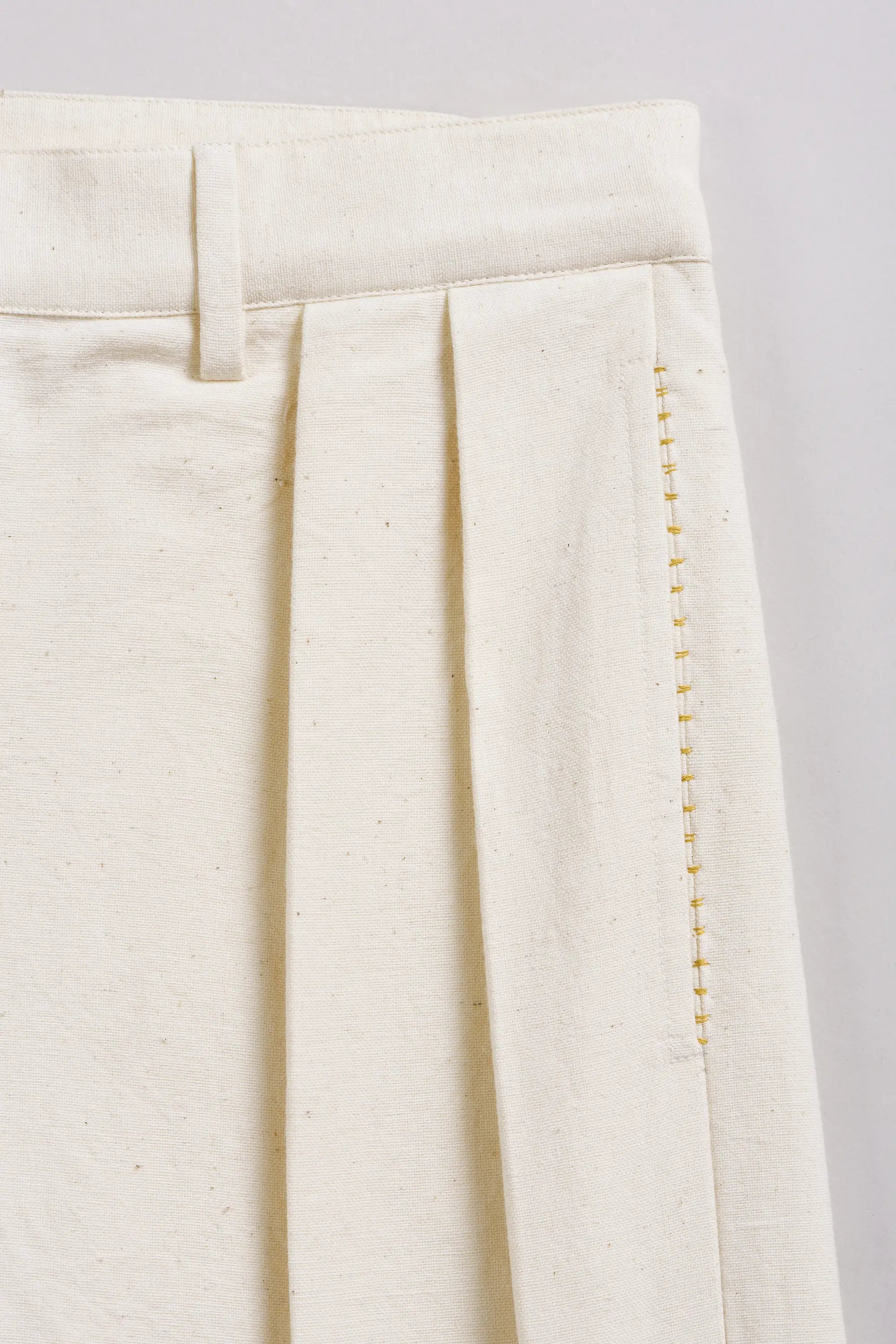 Close-up of a ecru fabric with hand detailing on a light grey background
