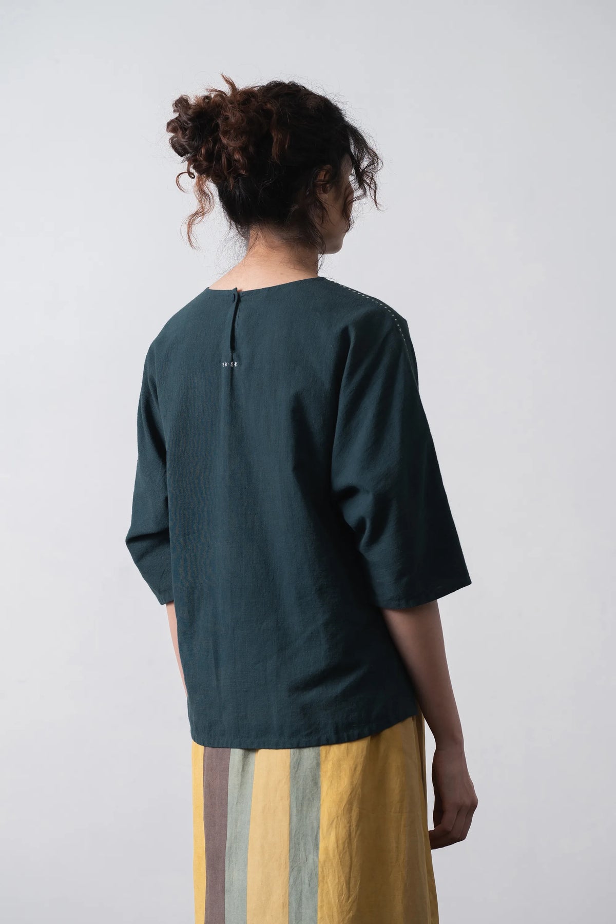 Back shot a woman wearing cotton black indigo top with hand details