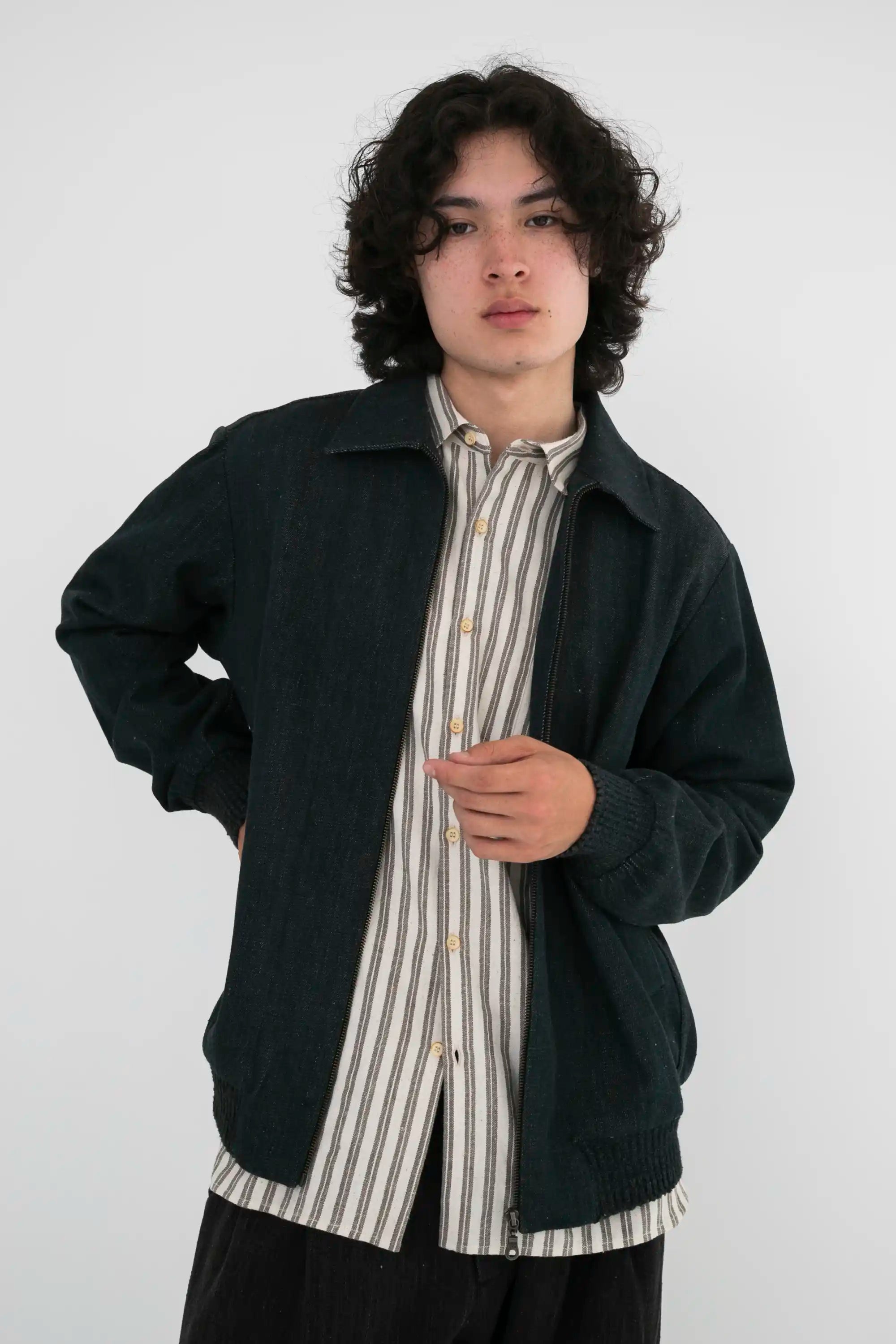 Man wearing a midnight indigo jacket over a striped shirt on a grey background