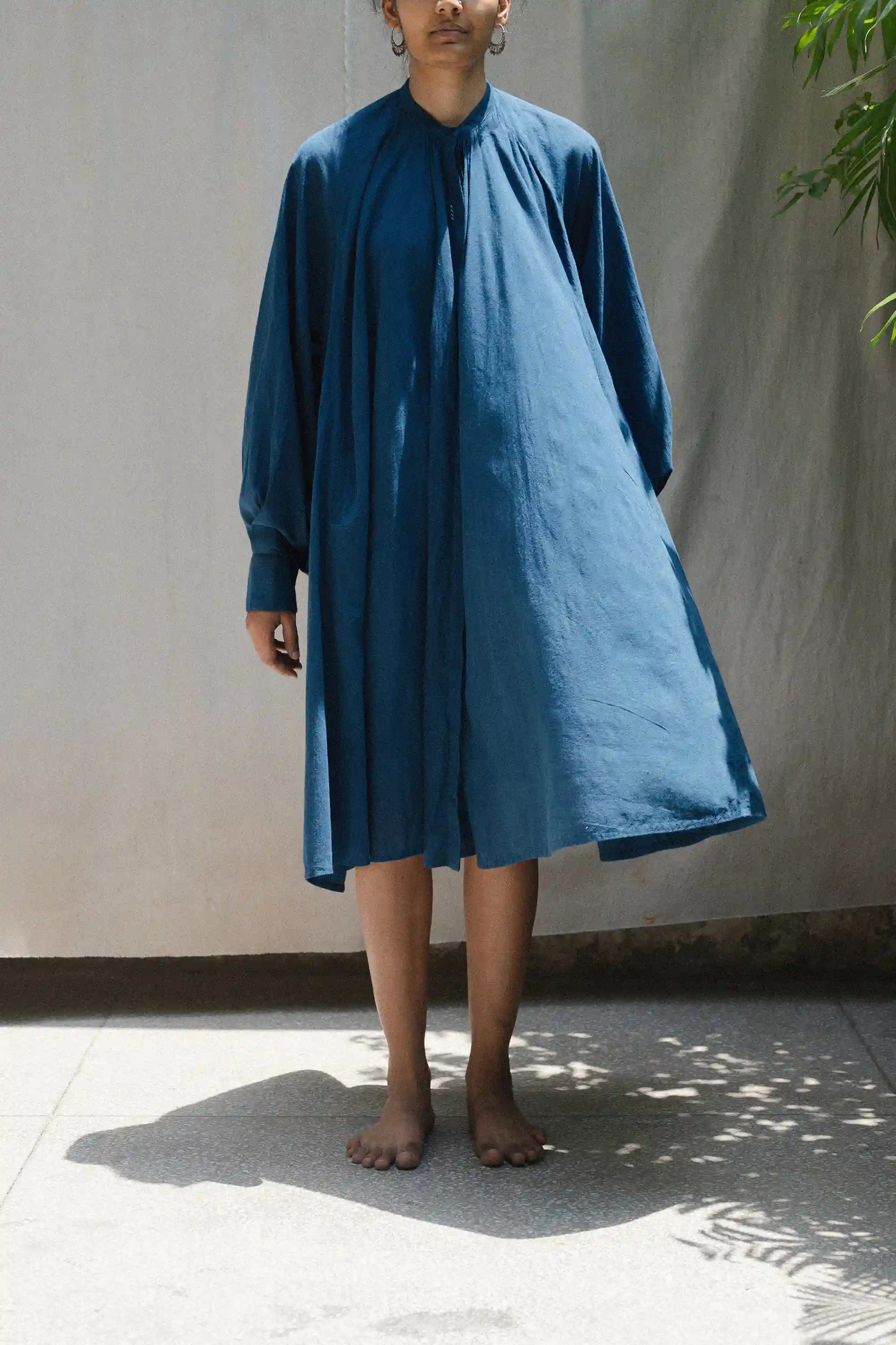 Person wearing a blue dress standing against a plain background