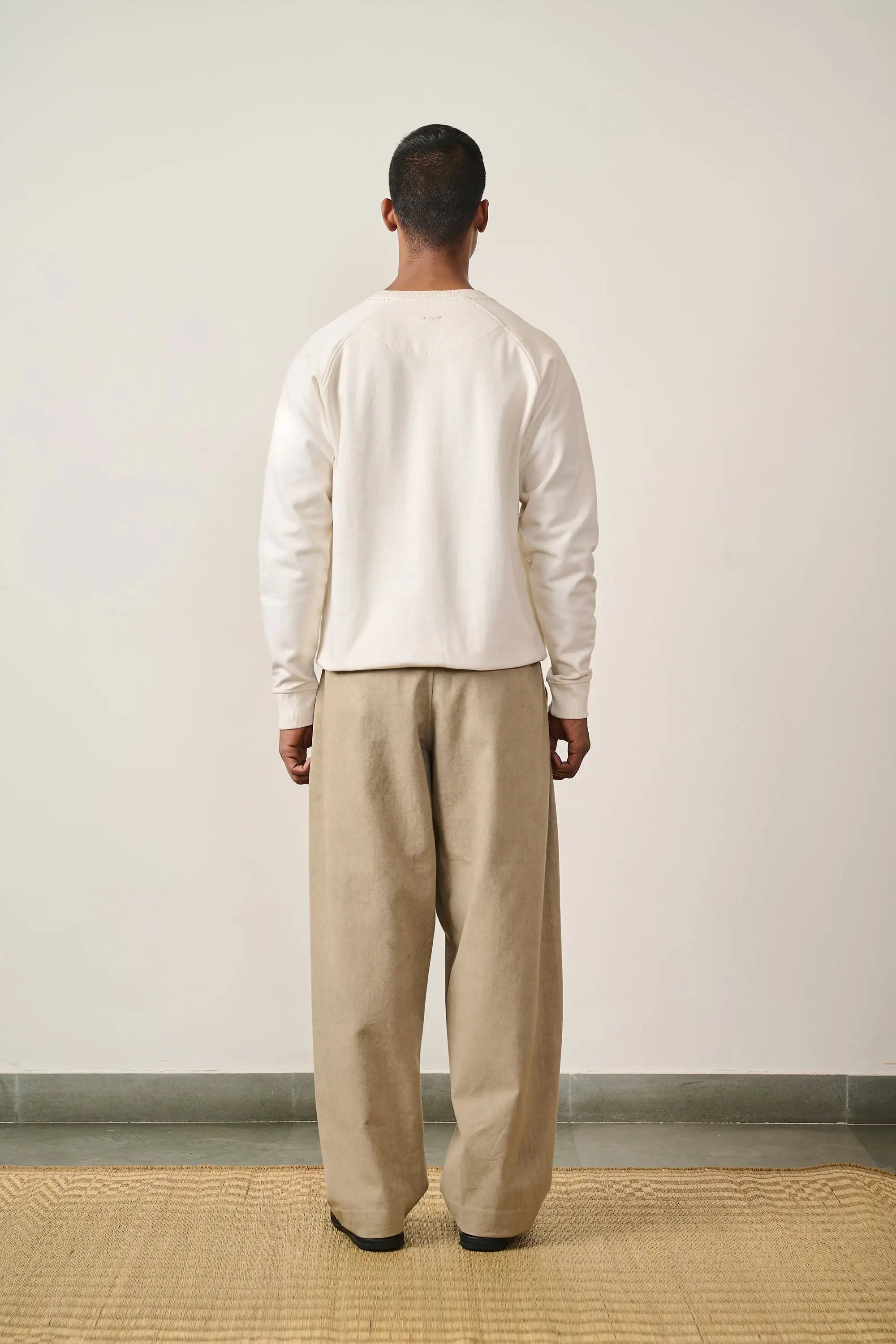 A back shot of a man wearing ecru sweatshirt