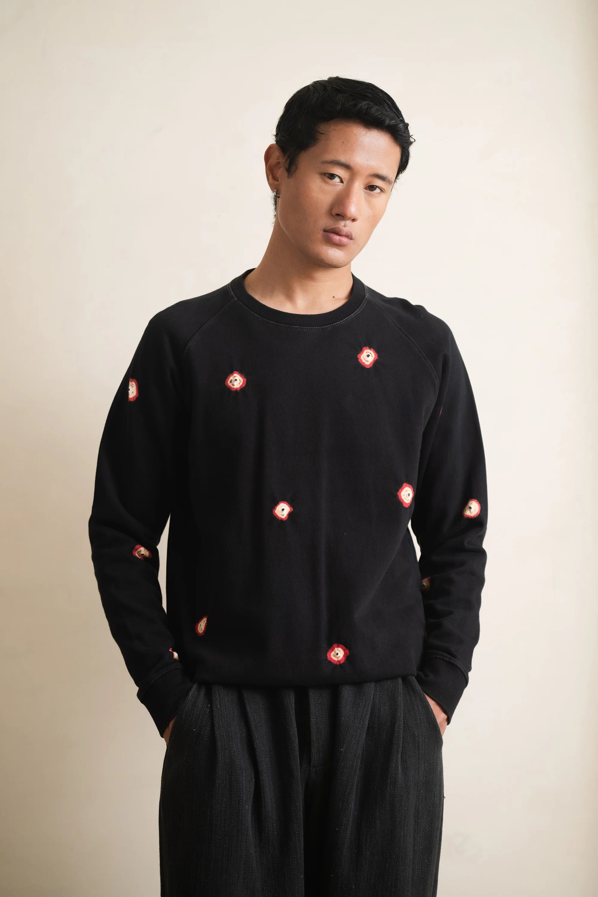 Man wearing a black sweatshirt with shibori against a light grey background