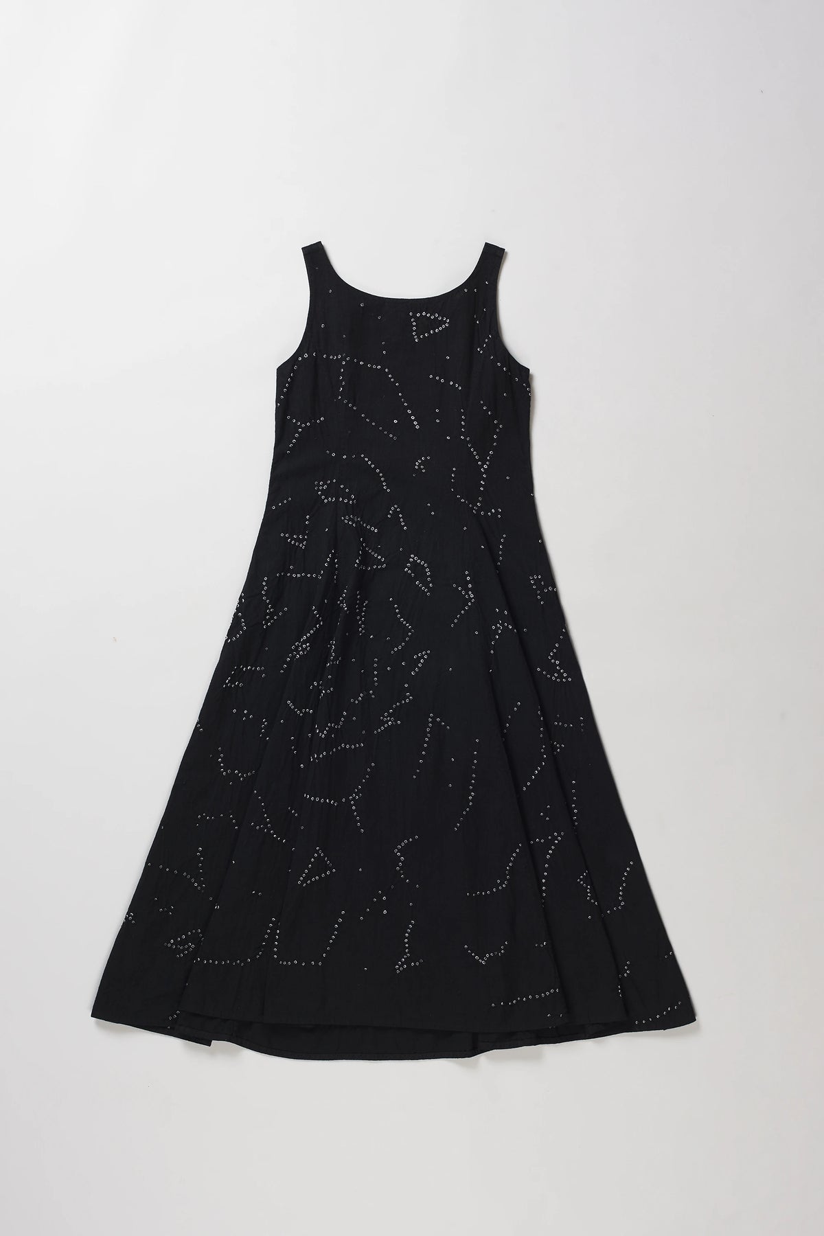 Back shot of sleeveless black A-line dress with a shibori pattern, displayed flat against a light grey background.