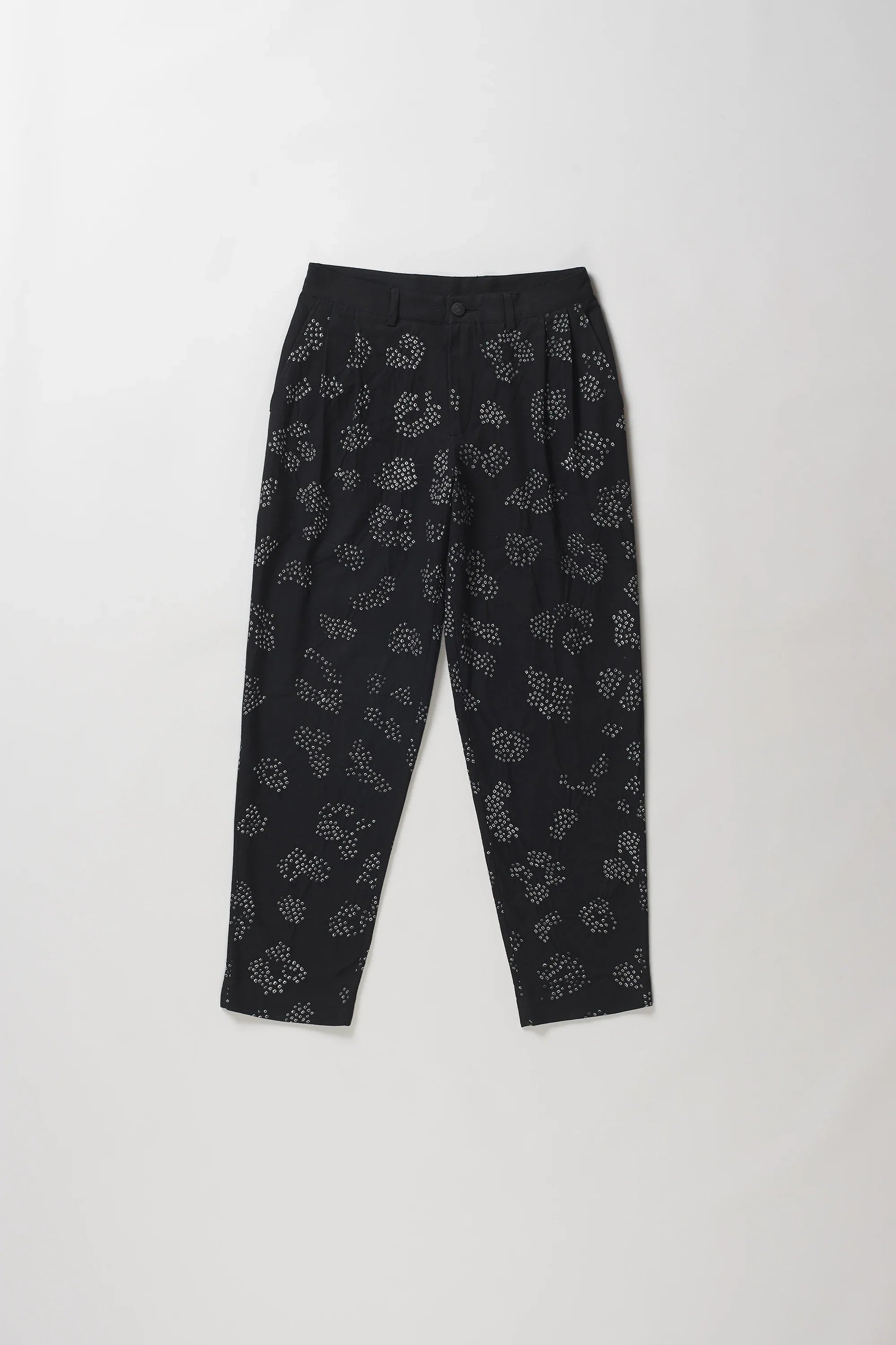Black trousers with a white floral bandhani, laid flat against a light grey background.