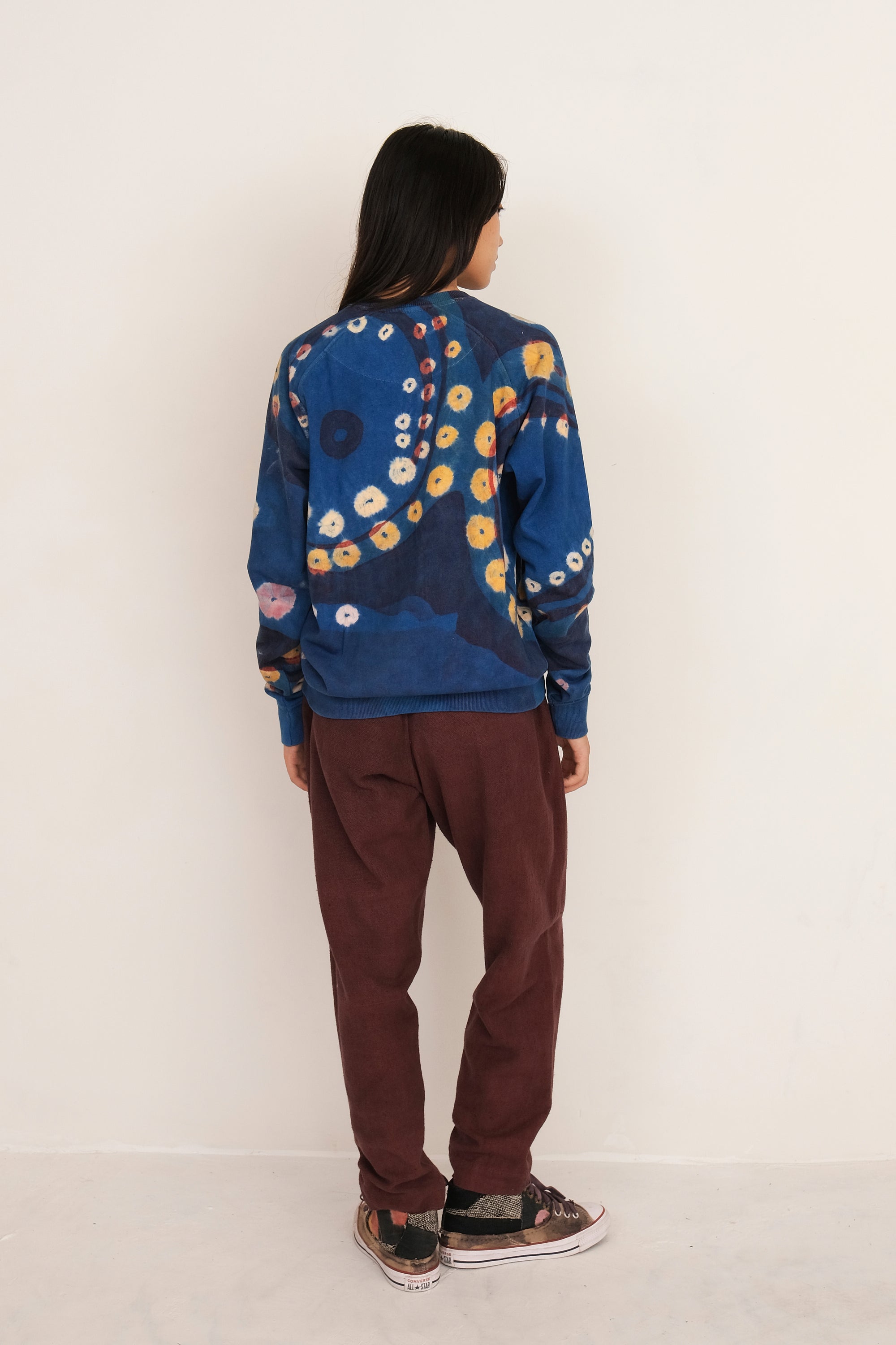 A back shot of a woman wearing medium indigo sweatshirt