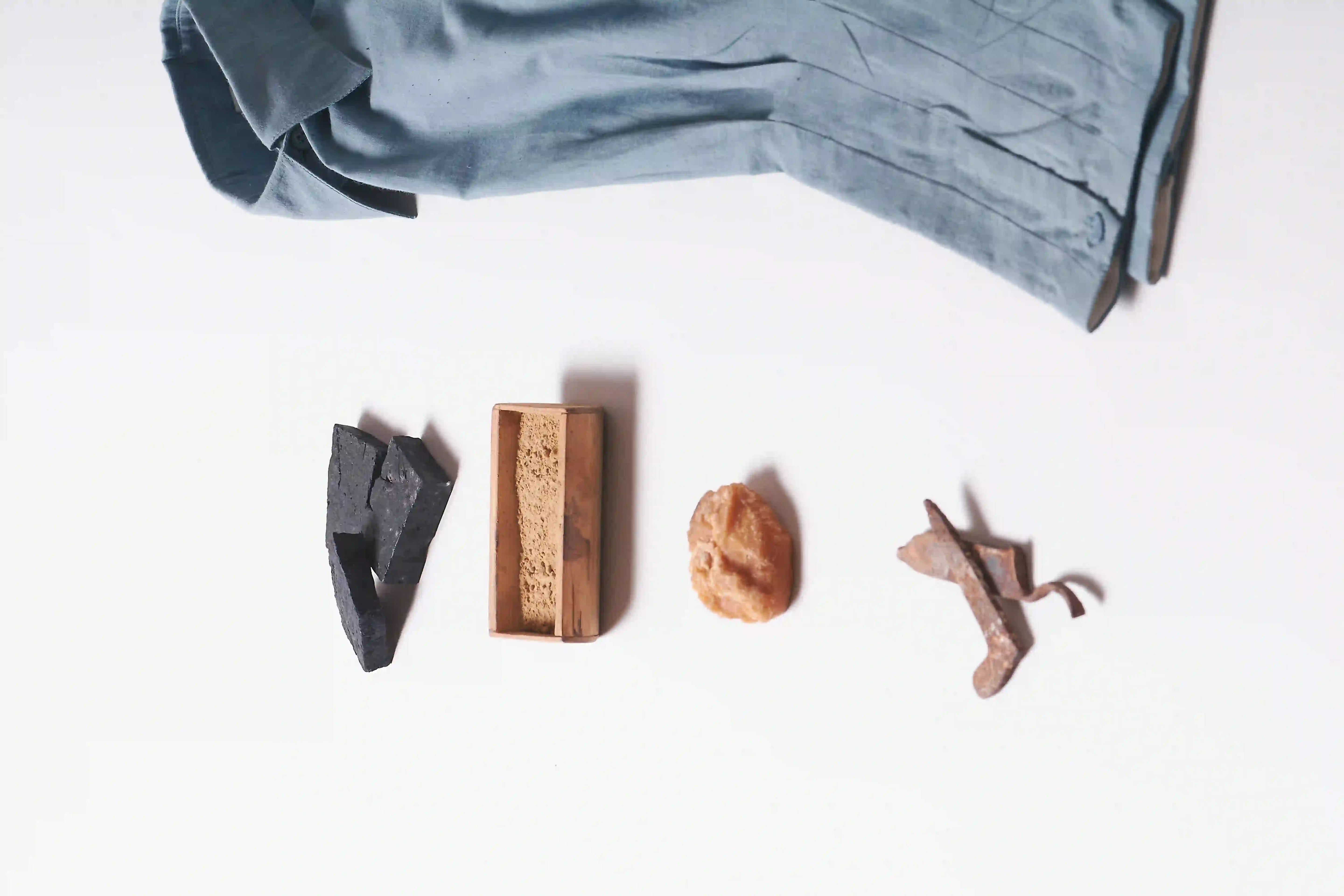 Decorative items including a folded powder blue fabric, wooden block, and stone on a white surface.