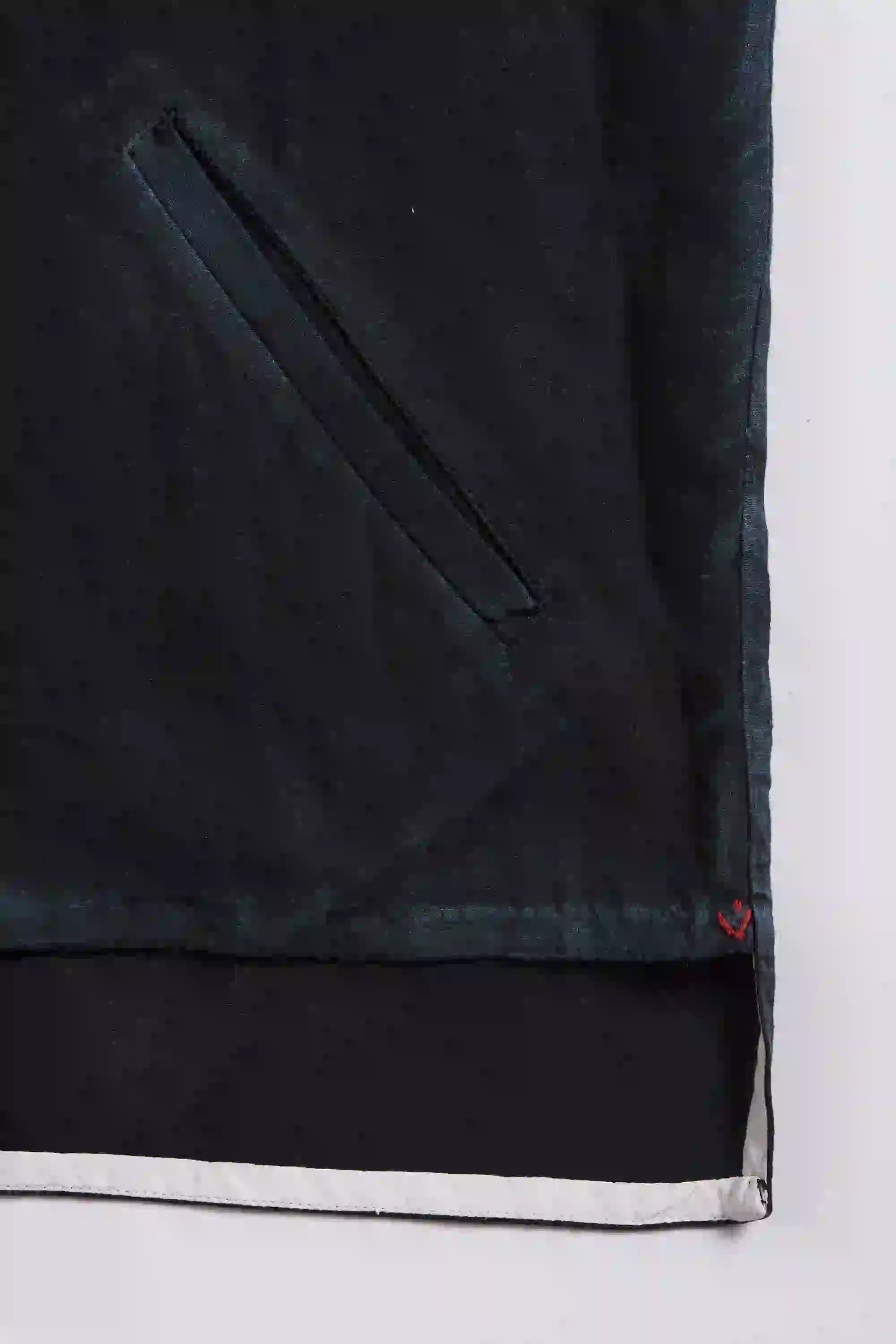 Close-up of a black fabric with a white border and red small pehchan on a light grey background