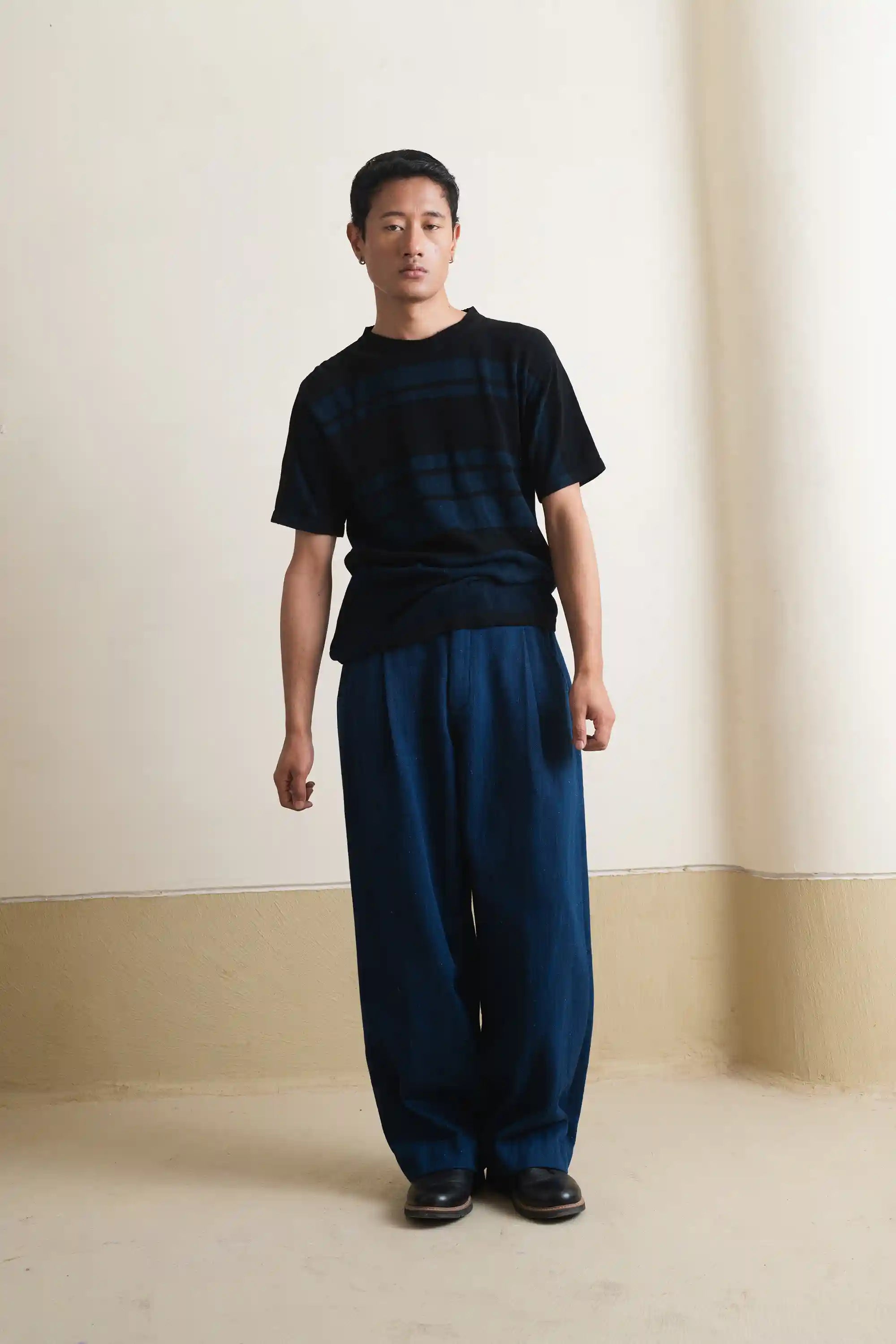 A man wearing black knitted t-shirt with indigo pant