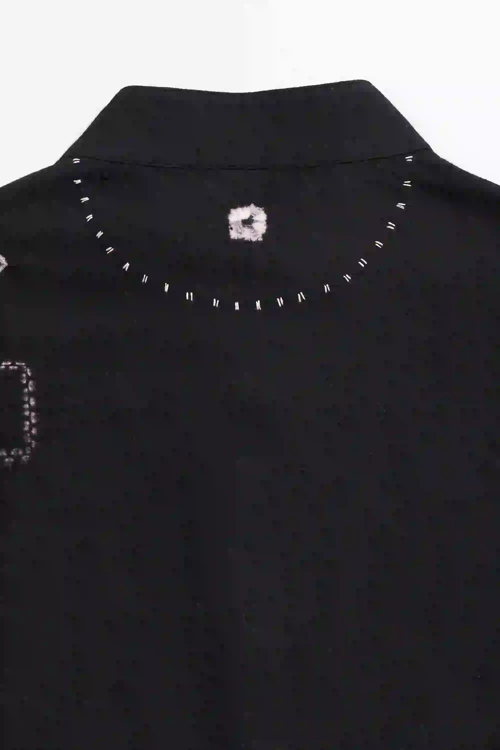 Close-up of a black garment with decorative elements on a white background