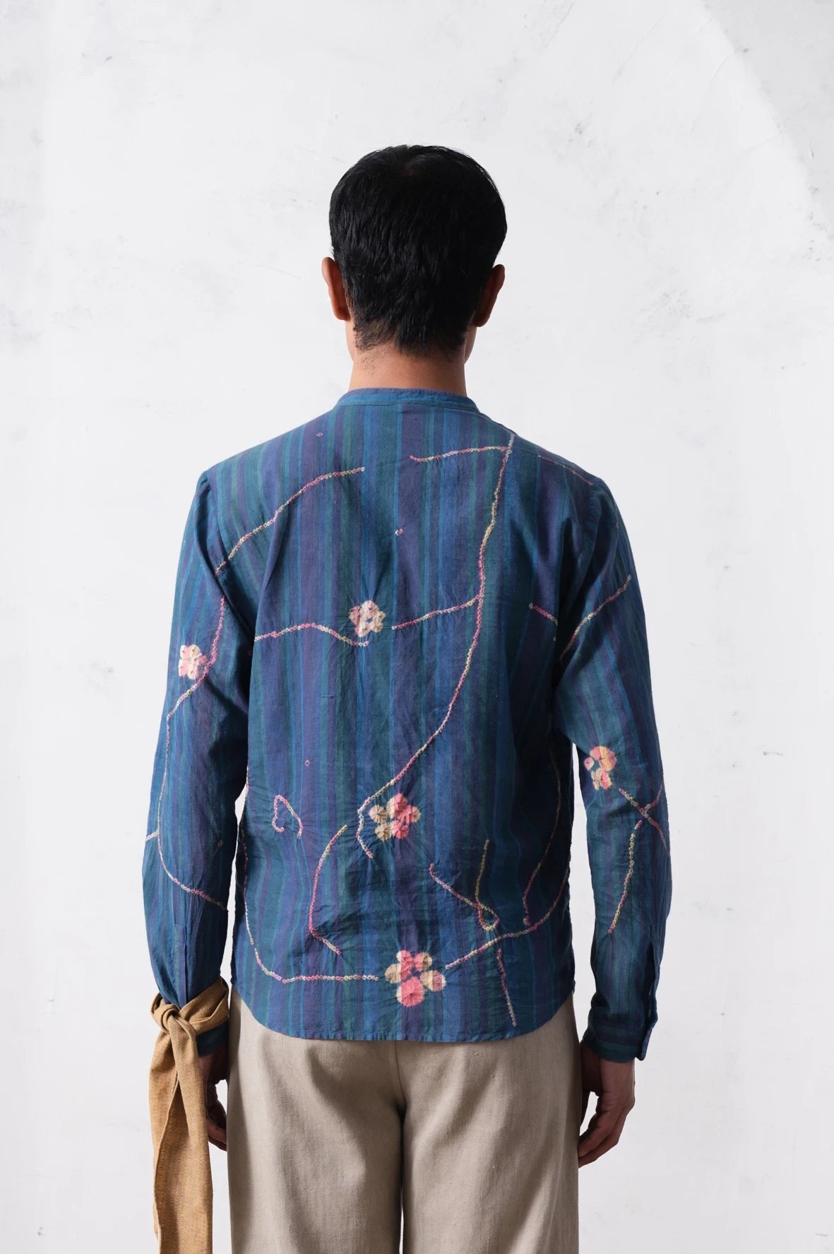 A back shot of a man wearing blue shirt with hand shibori
