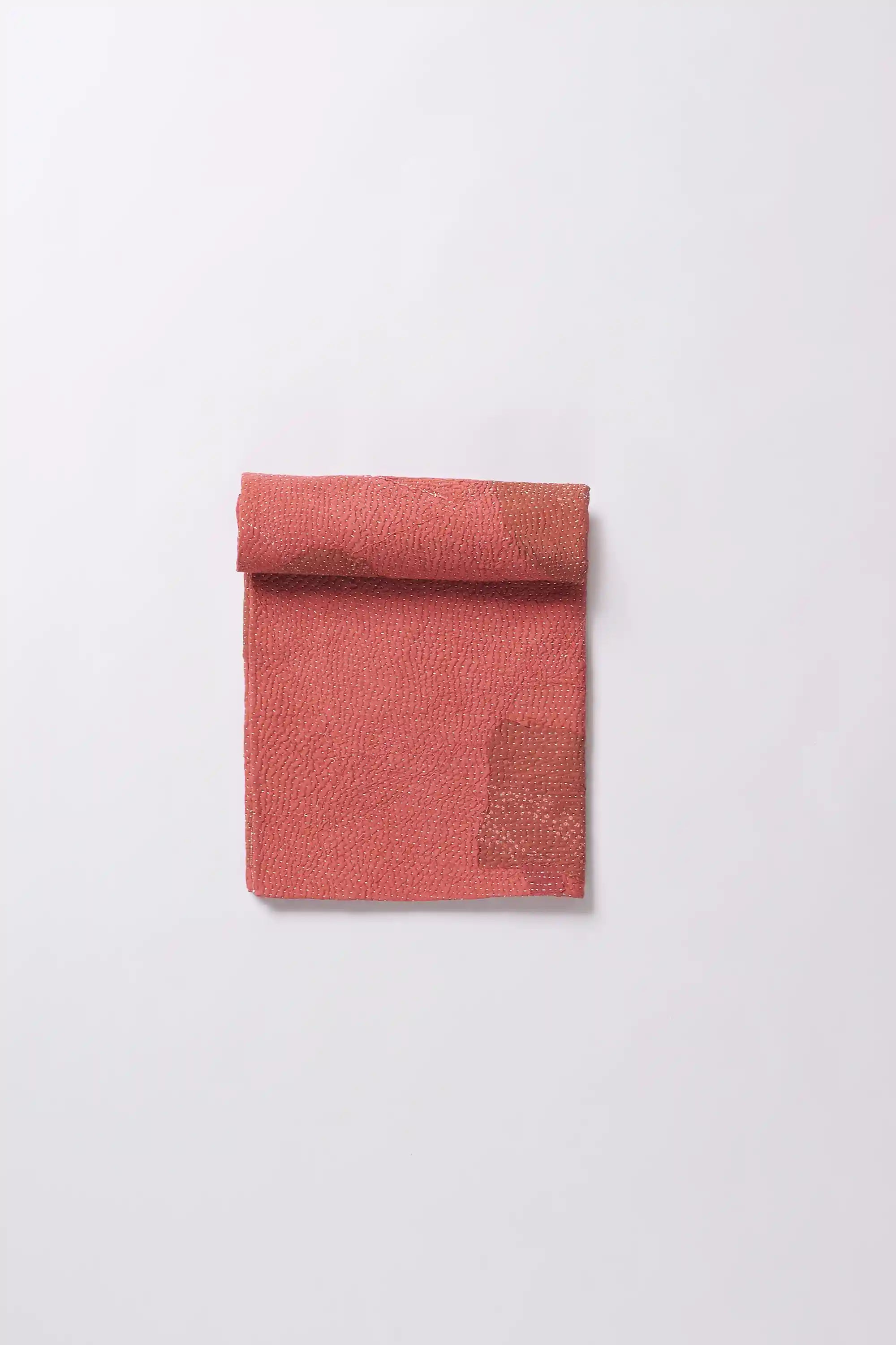 A red quilt roll on a light grey background