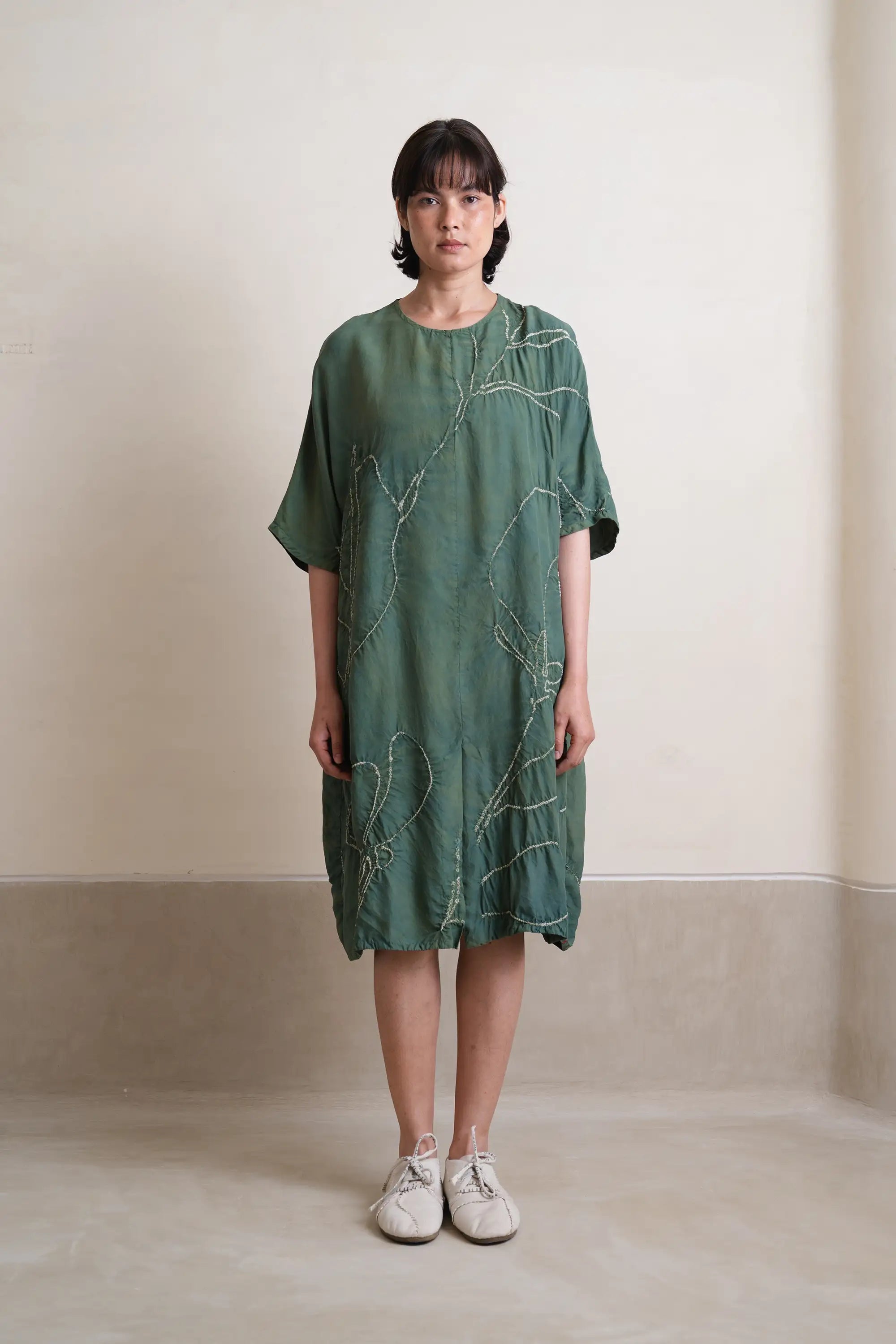 A woman wearing silk olive green dress