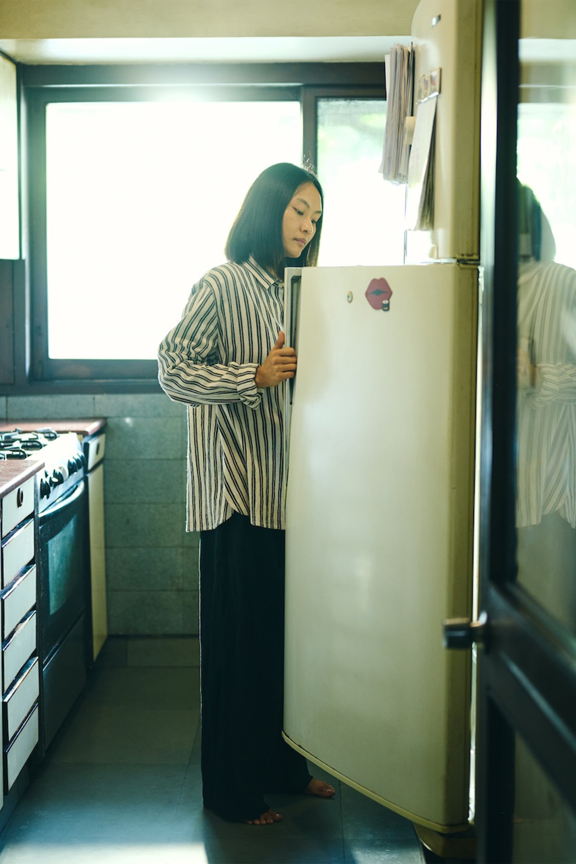 A woman wearing medium indigo cotton yarn dyed stripes shirt