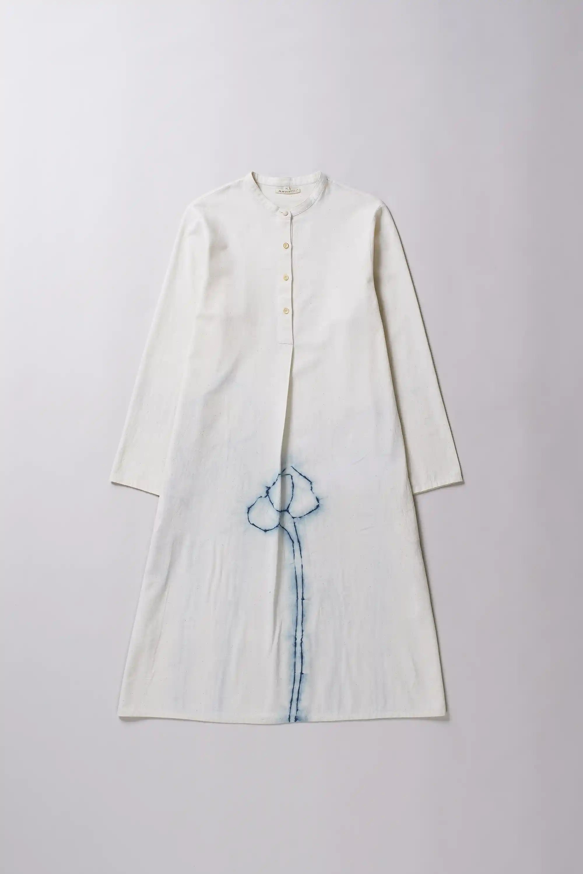 Ecru dress with a indigo shibori detail on a grey background