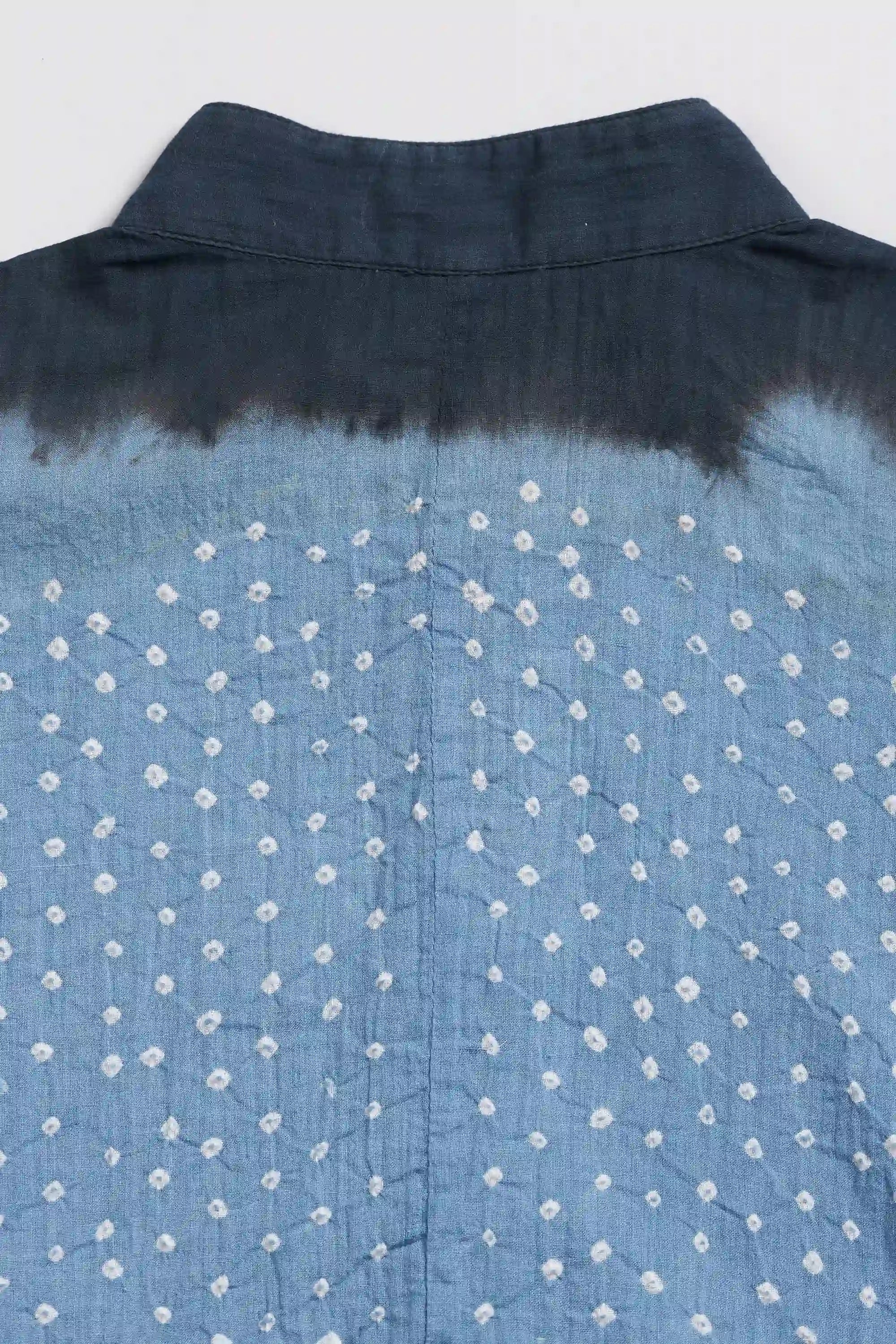 Close-up of light indigo fabric with a white shibori tie-dye pattern.