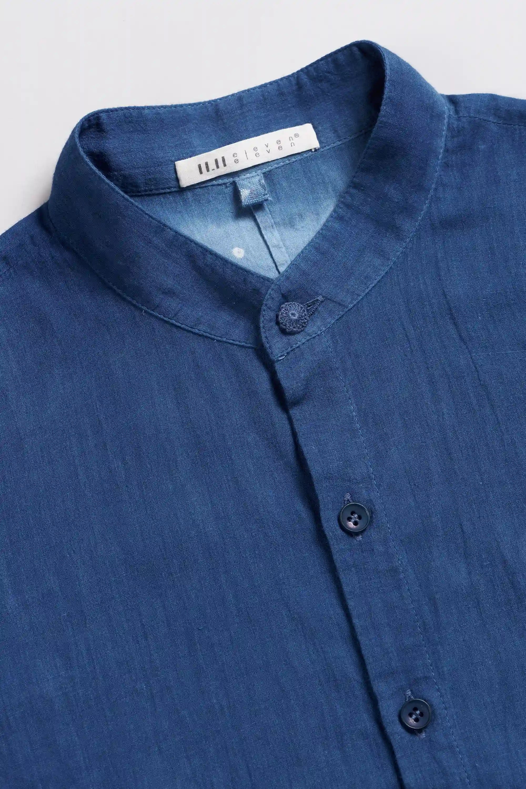 A close-up of a shirt with a mandarin collar and dark buttons.