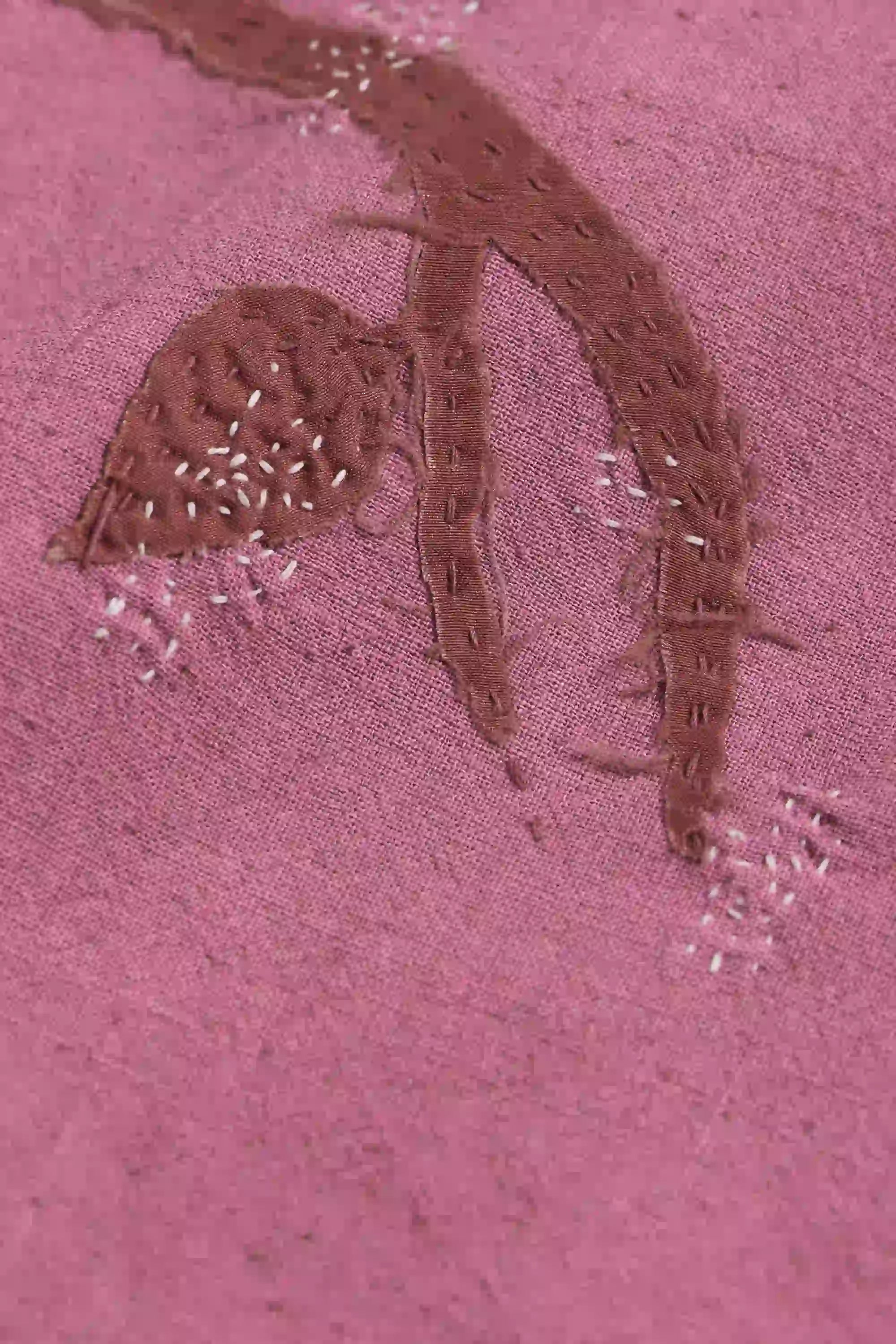 Embroidered design on a pink fabric with patchwork