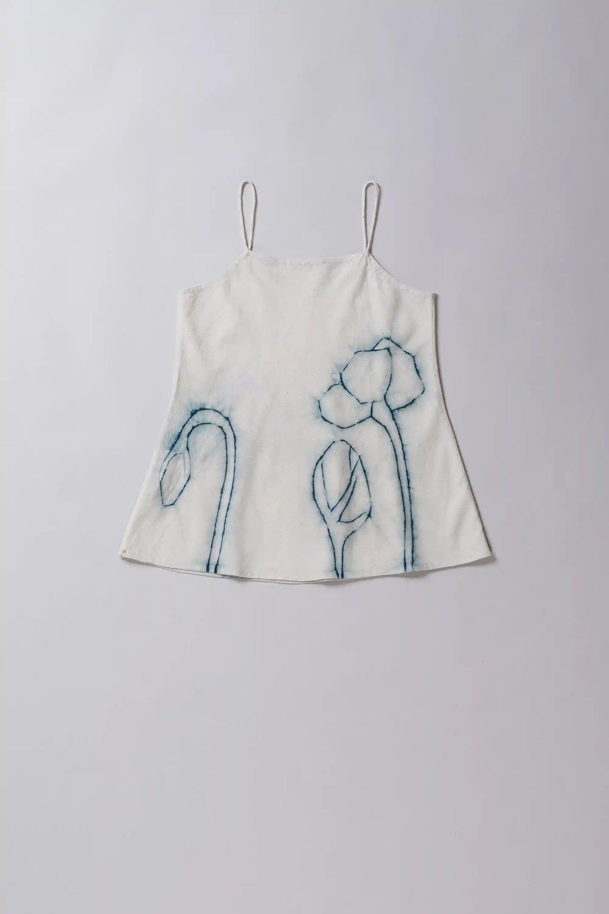 White top with blue floral embroidery on a light gray background