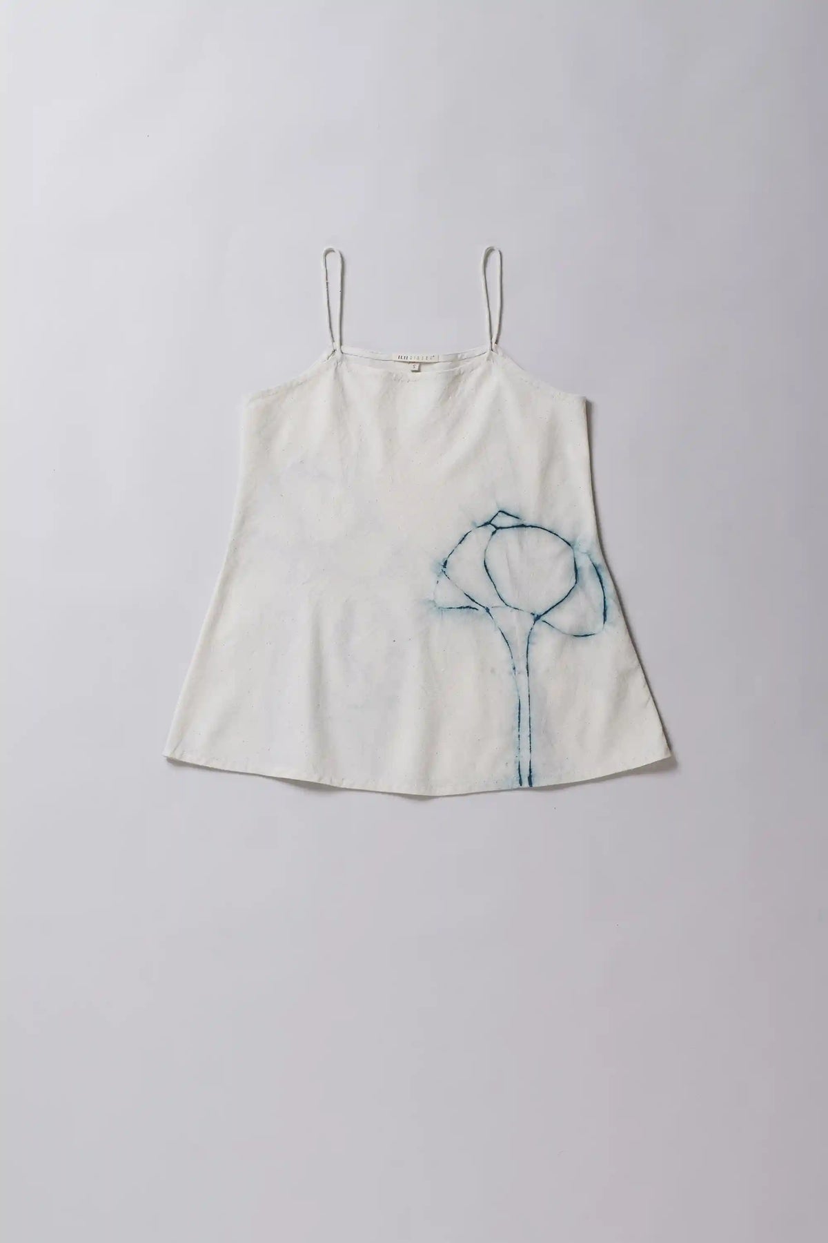 White slip dress with blue embroidery on a light gray background