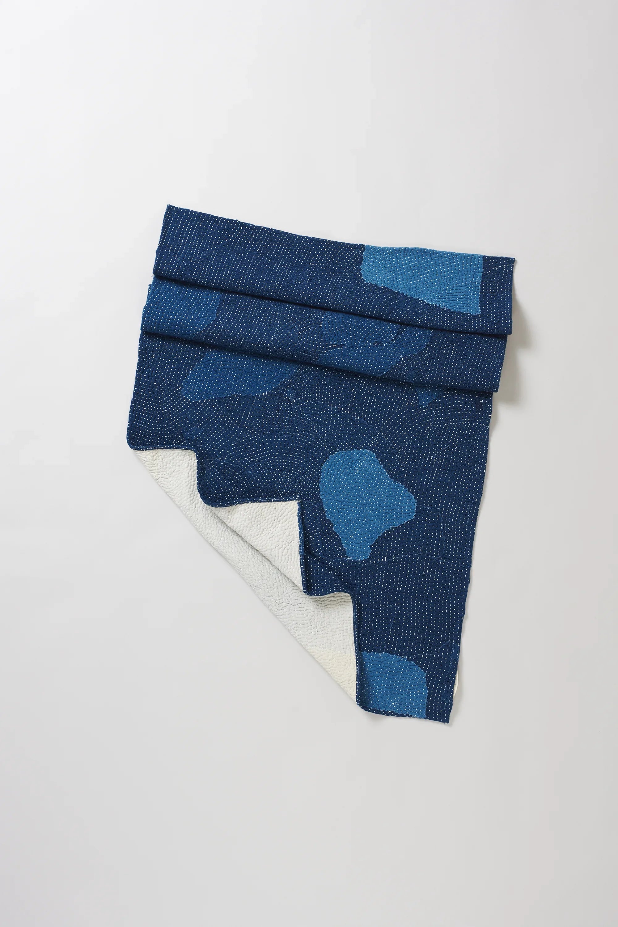 Indigo cotton patchwork quilt on a light grey background