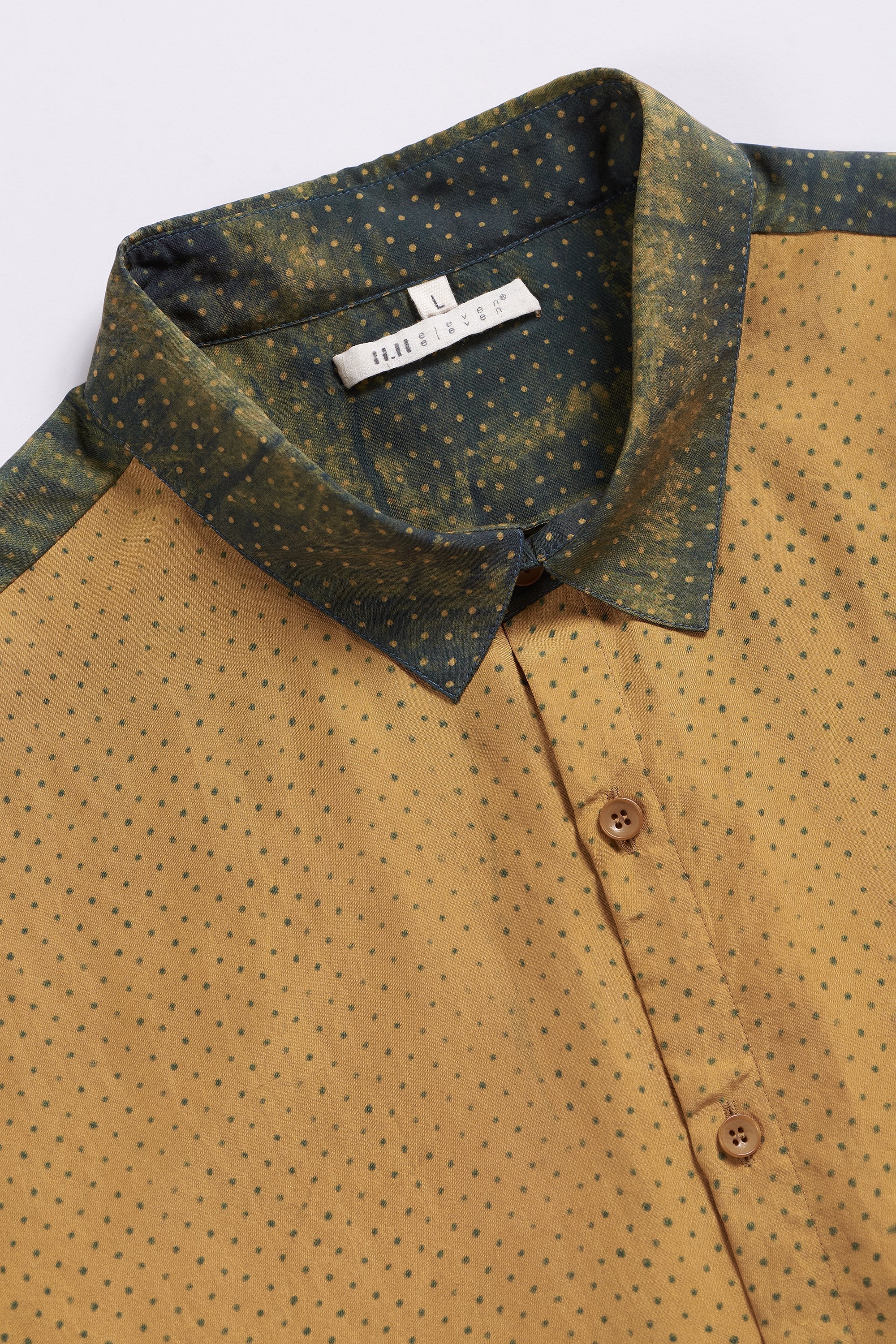 Close-up of a patterned shirt with a visible brand label on a white background