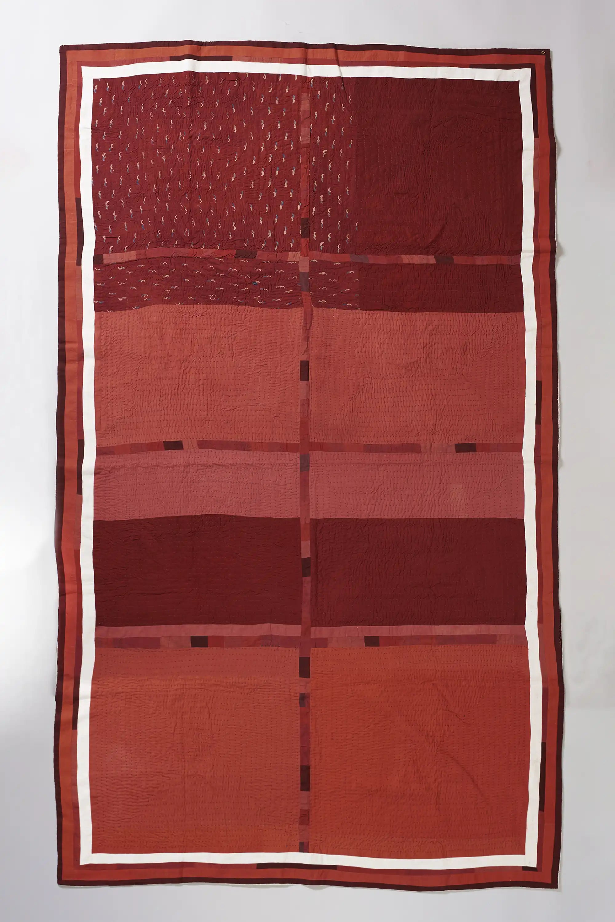 Red quilt with a geometric pattern on a light grey background