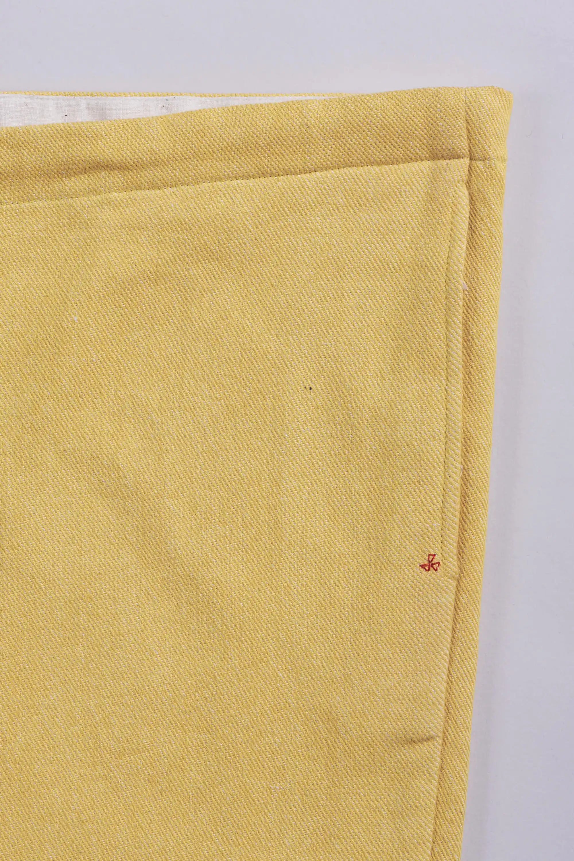 Close-up of a yellow fabric with a small red pehchan on a white background