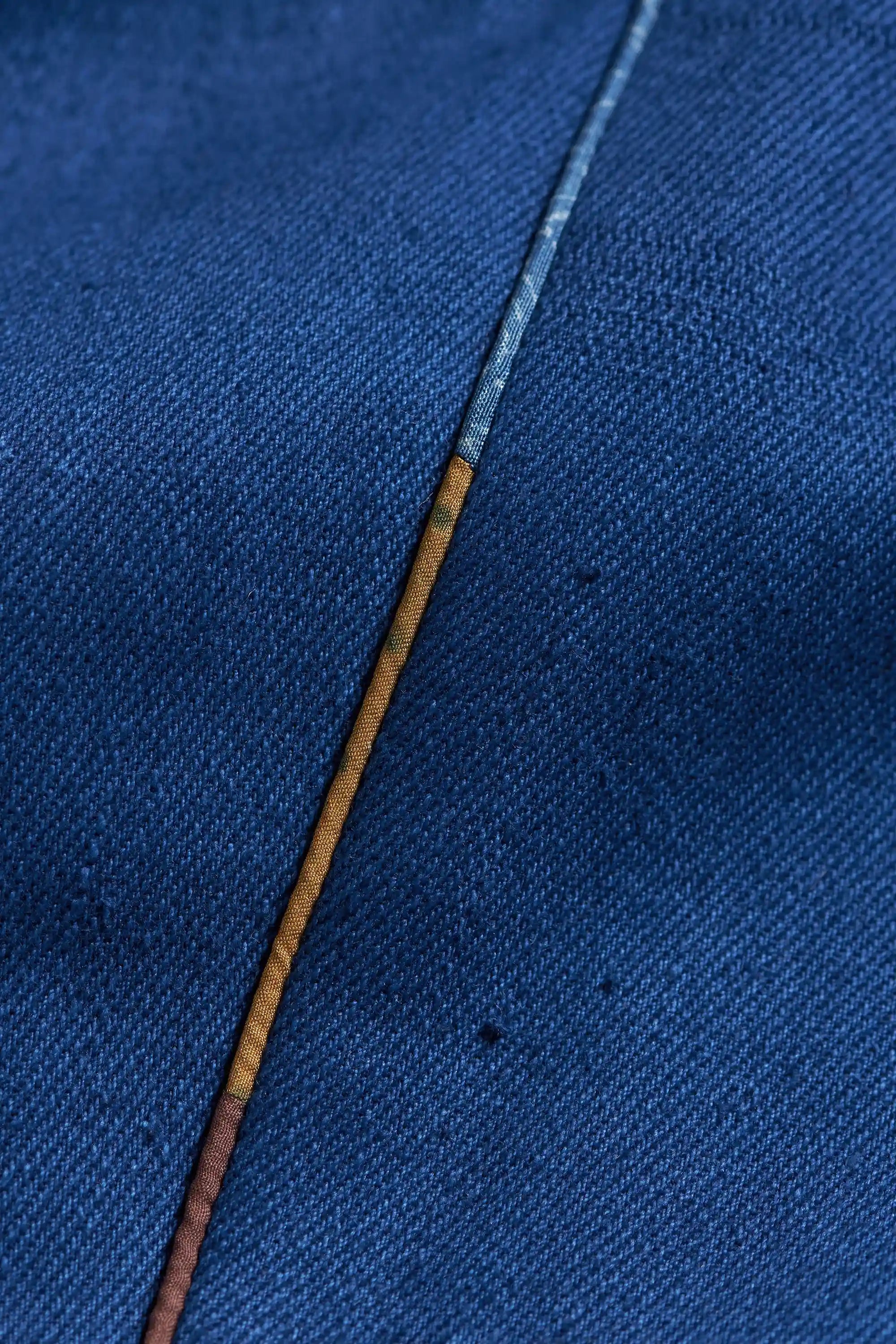 Close-up of a blue fabric with a brown thread running through it