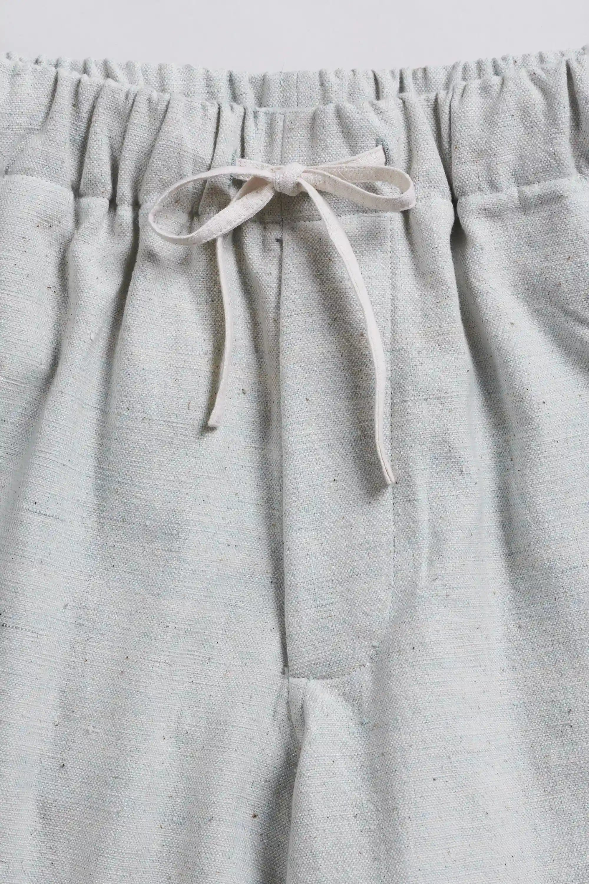Close-up of indigo pants with a drawstring on a light grey background