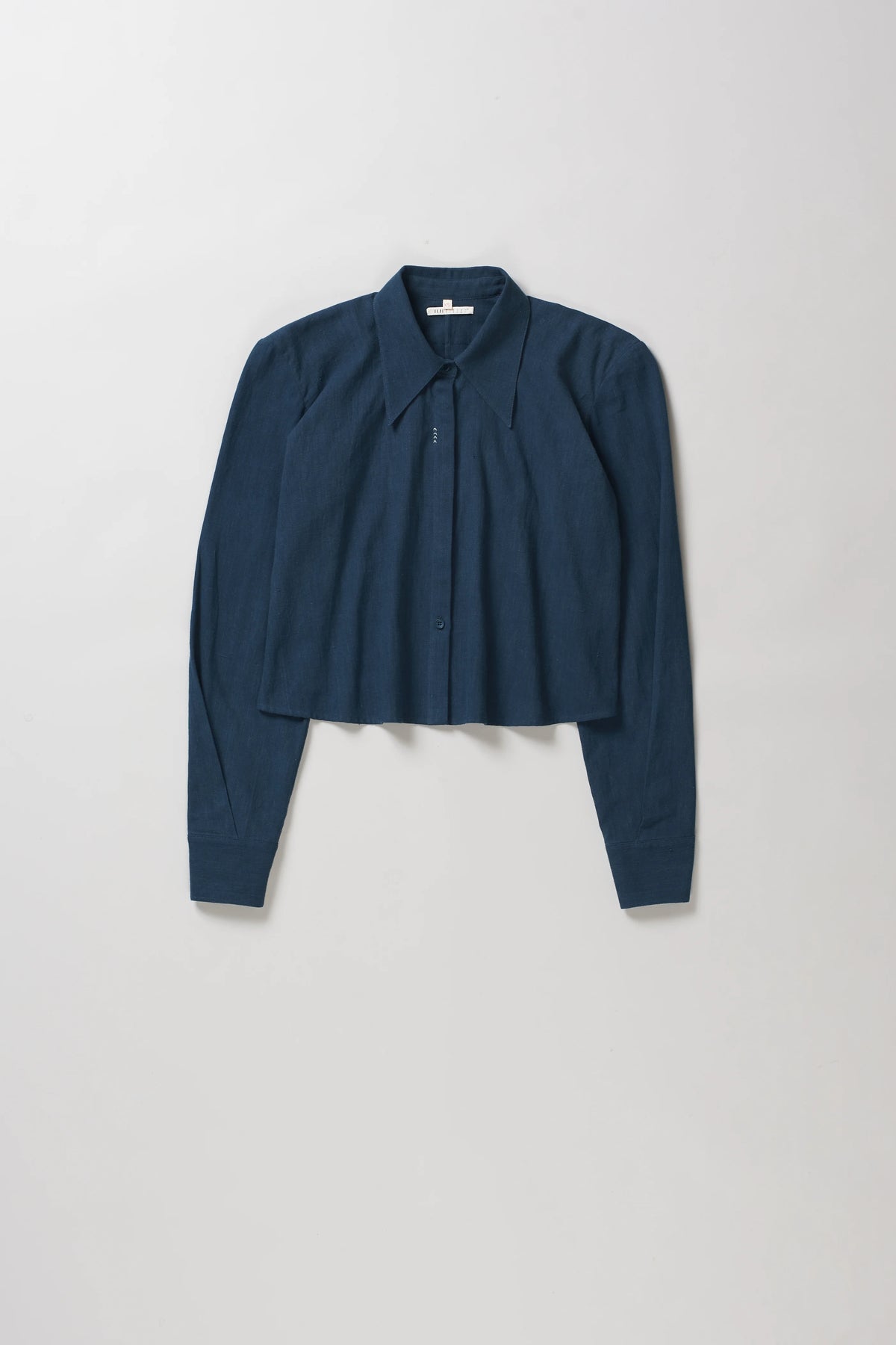 A black indigo cropped long-sleeve button-up shirt with a pointed collar, laid flat against a light grey background.