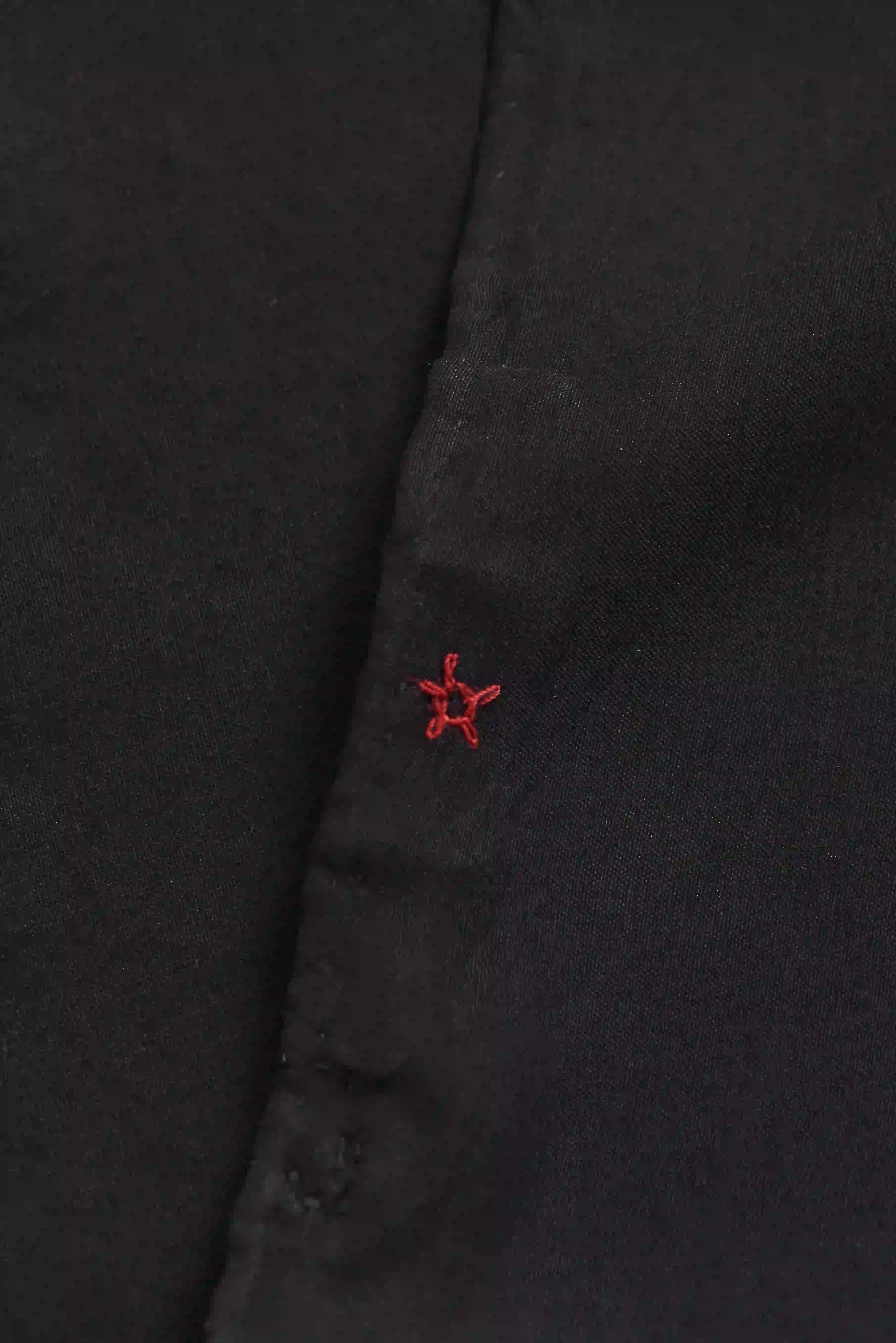 Close-up of a black fabric with a red embroidered star design.