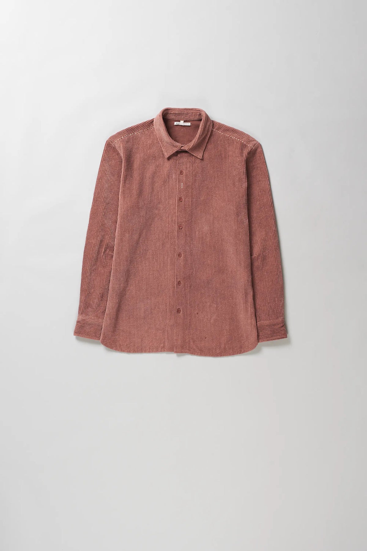 A rough pink corduroy button-up shirt with a pointed collar and long sleeves, laid flat against a light grey background.