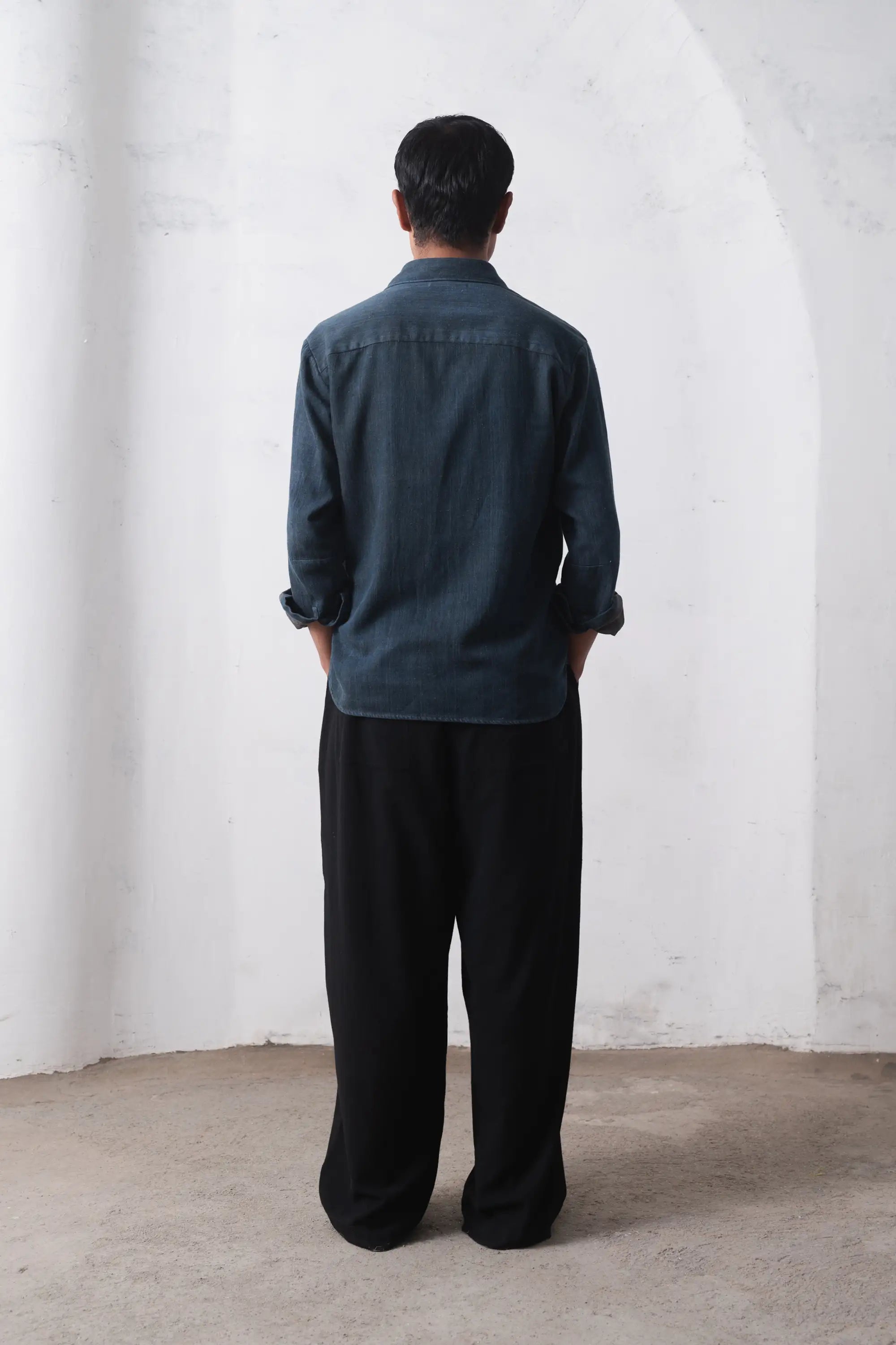 A back shot of a man wearing indigo shirt